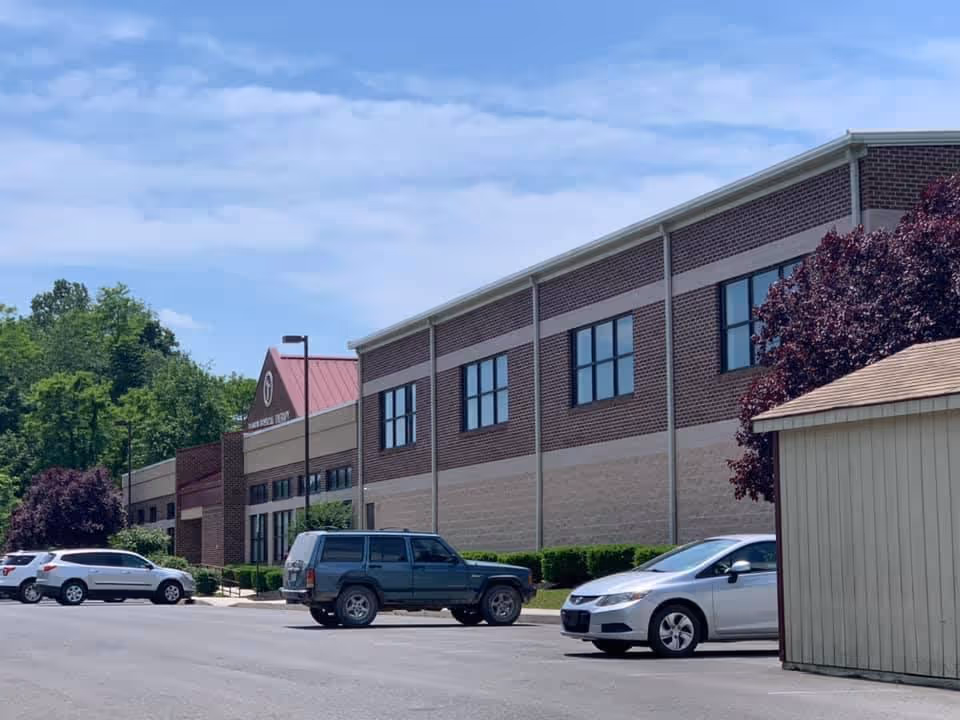Exterior view of Rankin Rehabilitation facility with parked cars and trees.