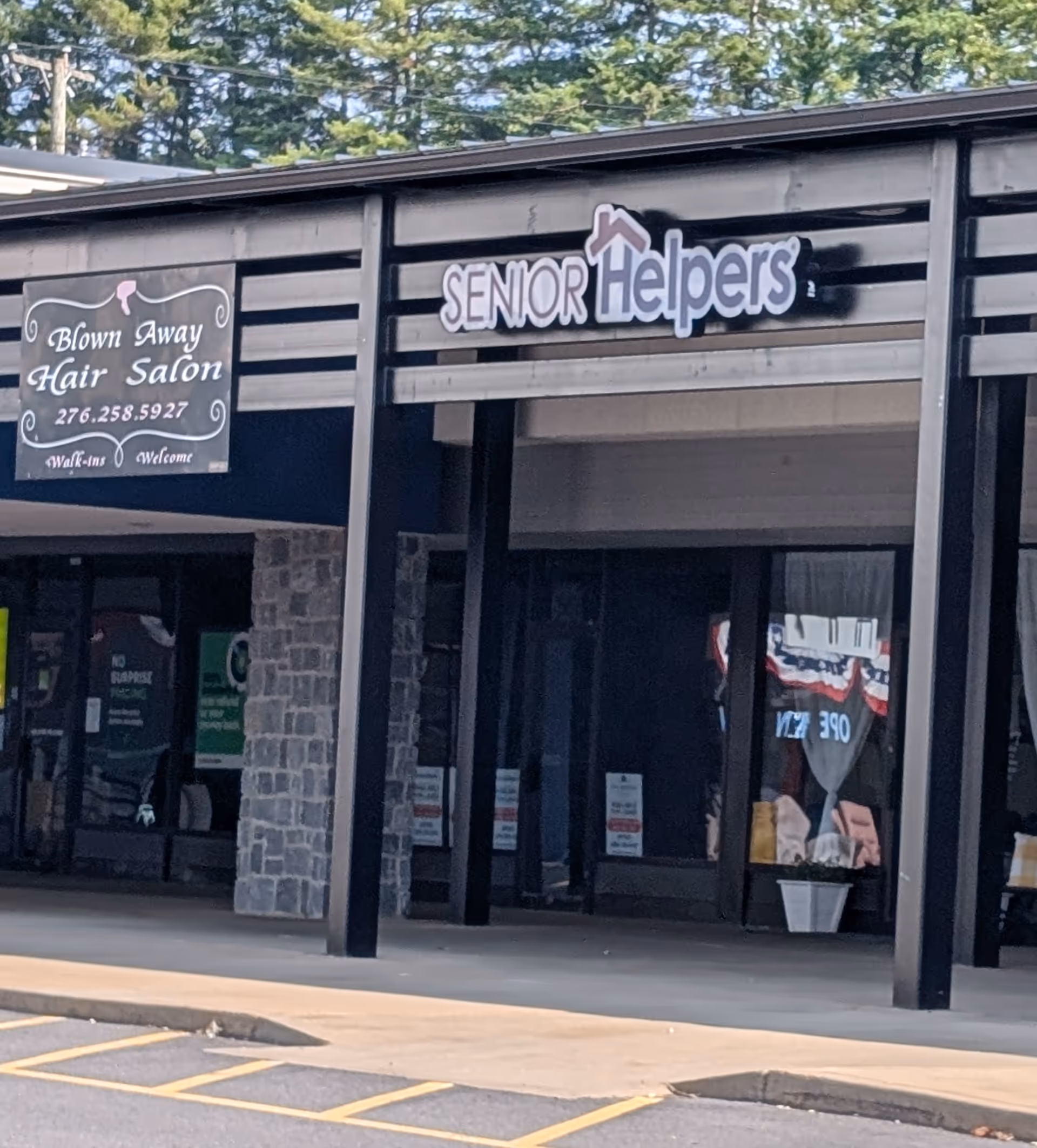 Exterior of a strip mall with a Senior Helpers sign and a Blown Away Hair Salon.