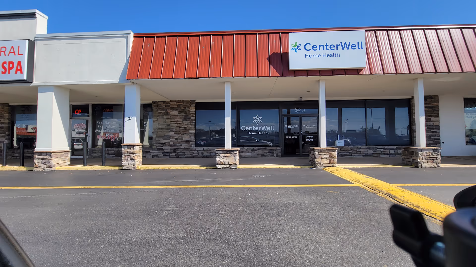 Front of a CenterWell Home Health storefront with stone accents and a red metal roof.