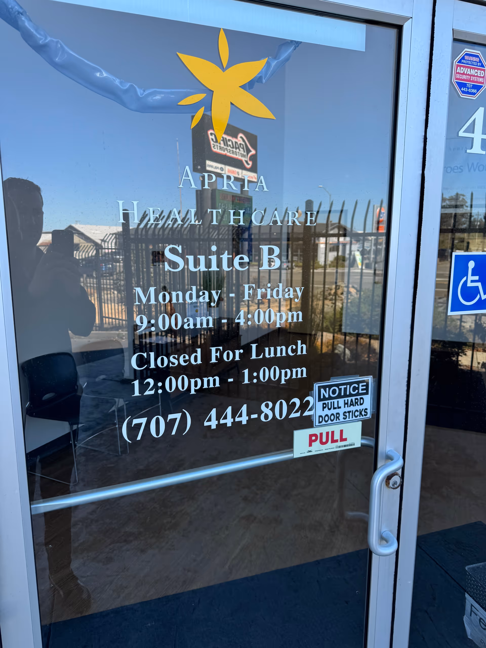 Glass door shows Apria Healthcare Suite B hours and notices.