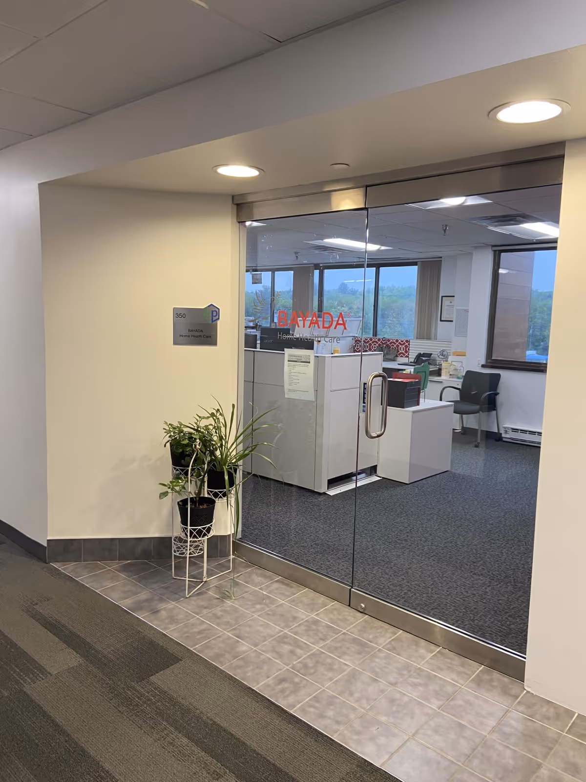 Glass entrance to BAYADA Home Health reception area with plants and desks.