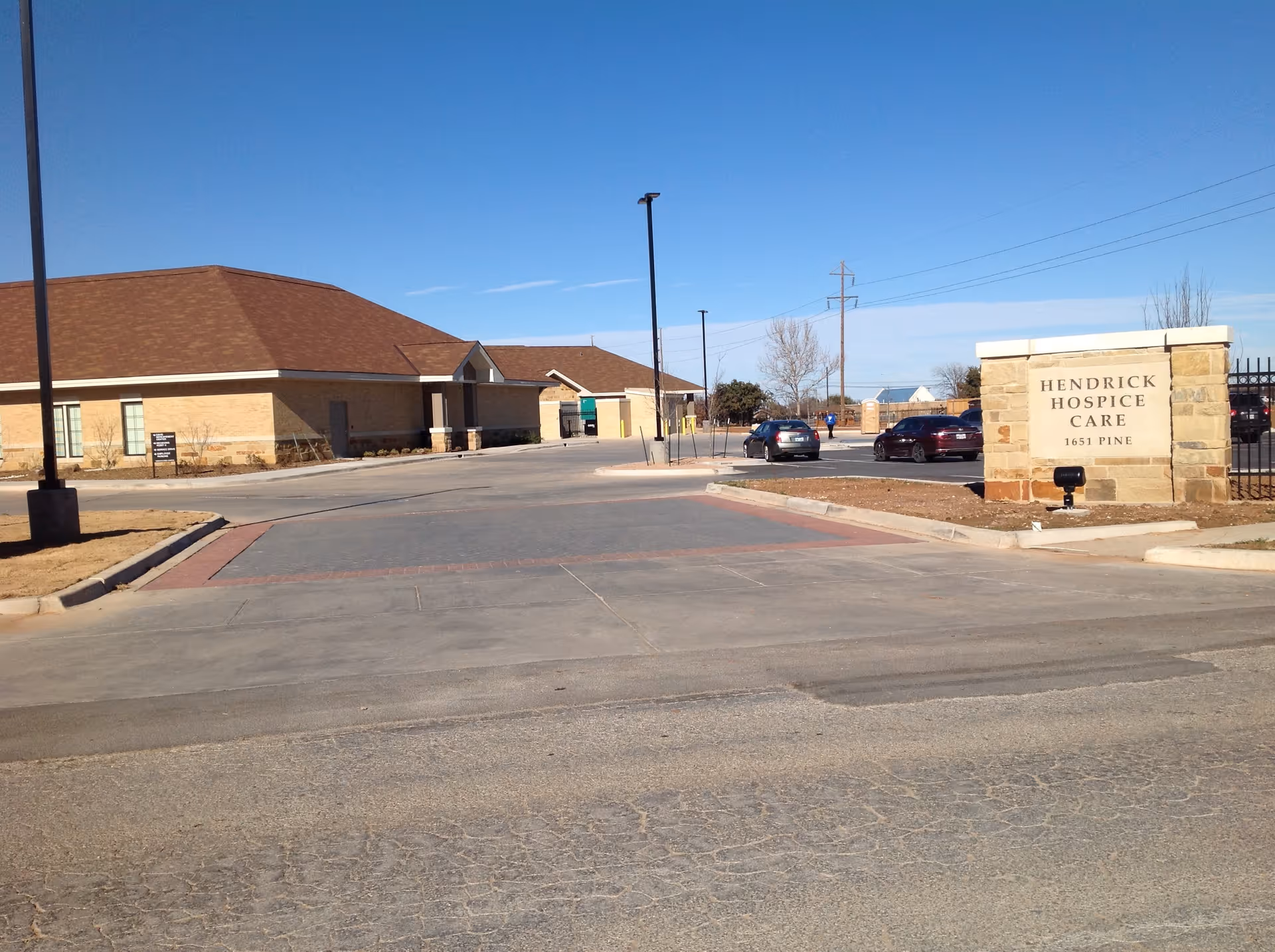 Exterior view of Hendrick Hospice Care facility with sign and parking area.
