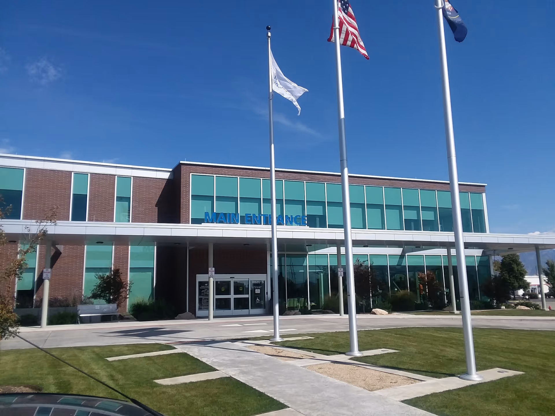 Exterior view of Intermountain Homecare & Hospice - South Jordan building with glass facade and flags.