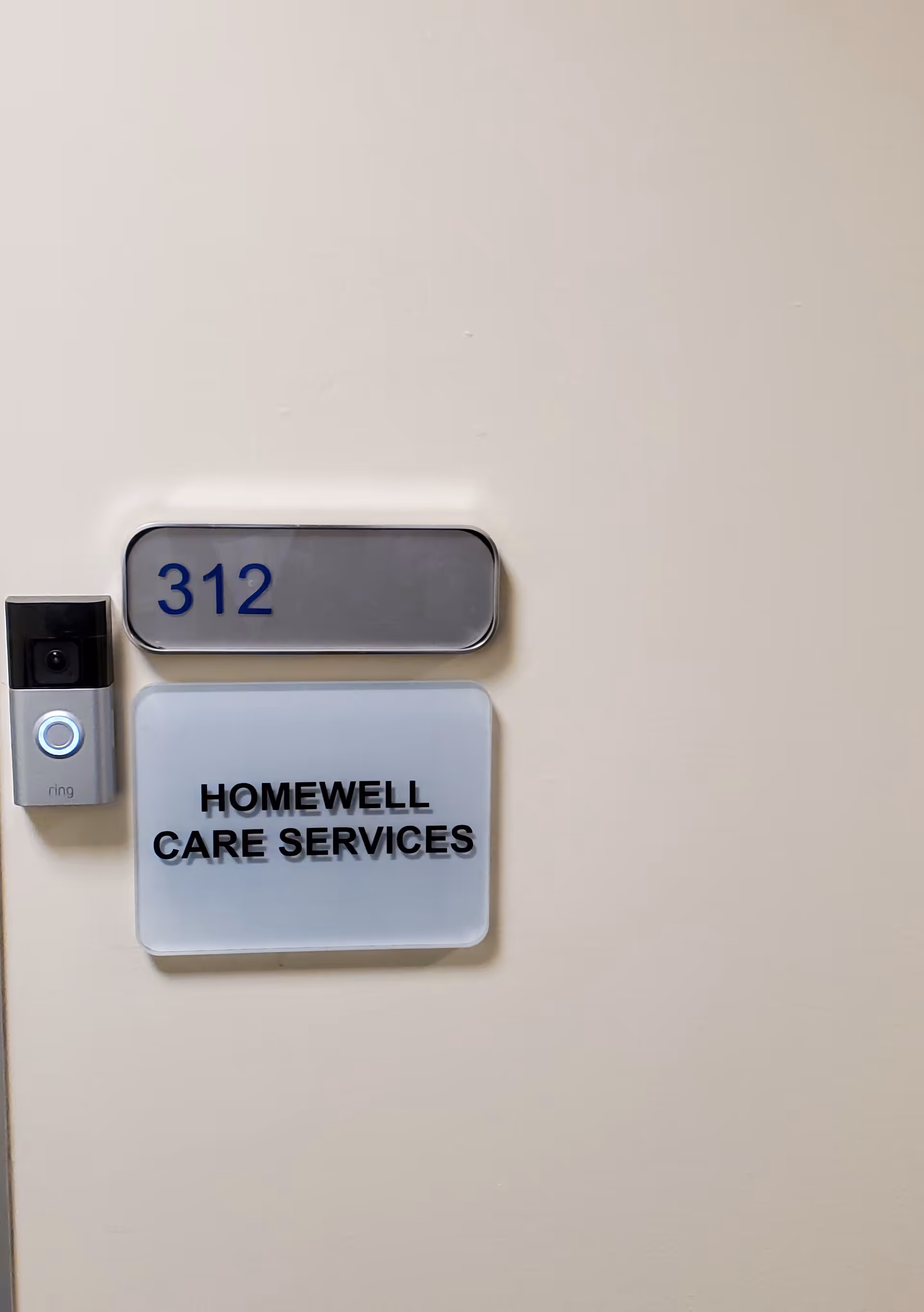 Door sign reading 312 and HomeWell Care Services on a beige interior wall.