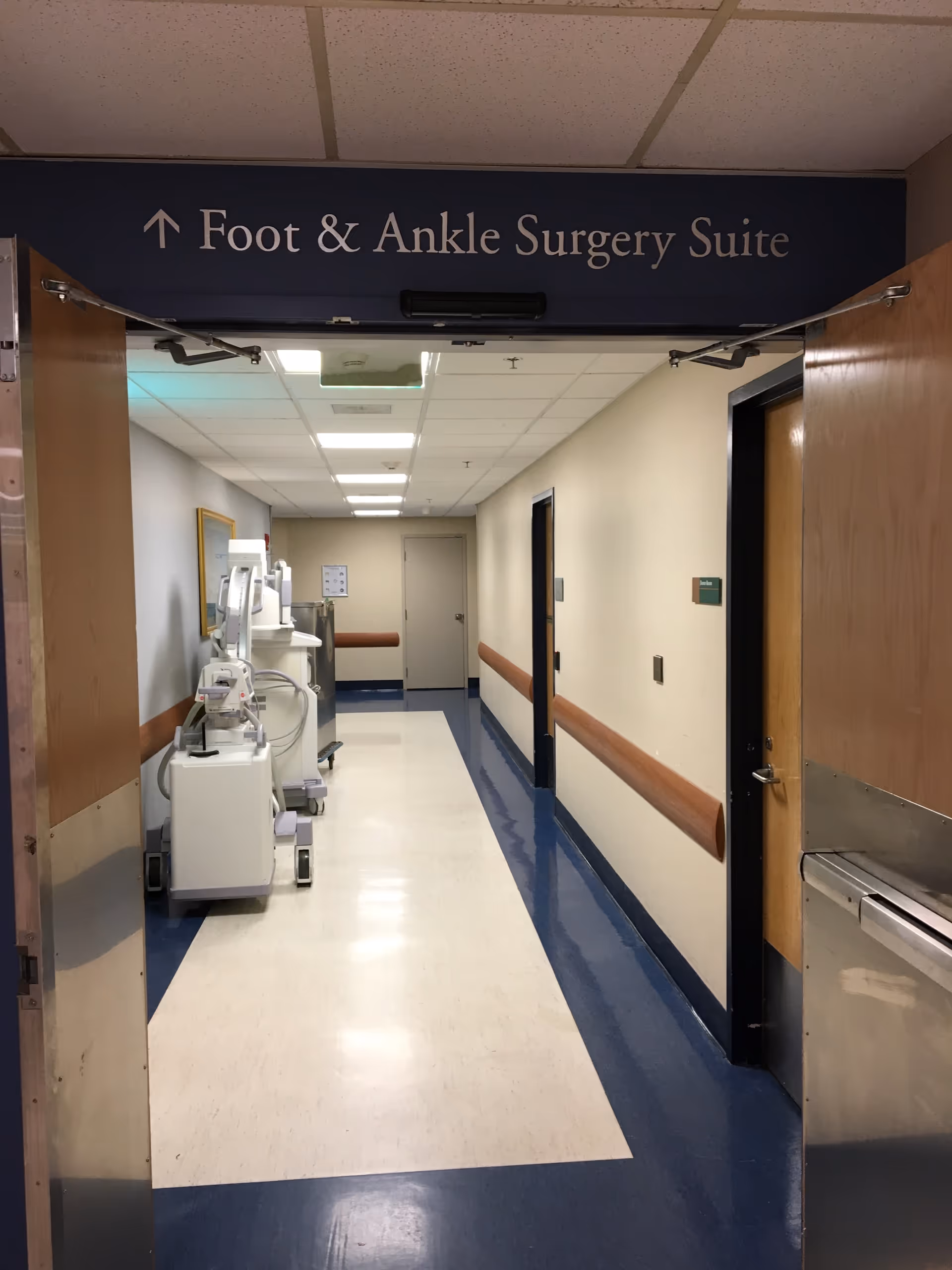 Hospital corridor with medical equipment on left; Foot and Ankle Surgery Suite sign overhead.