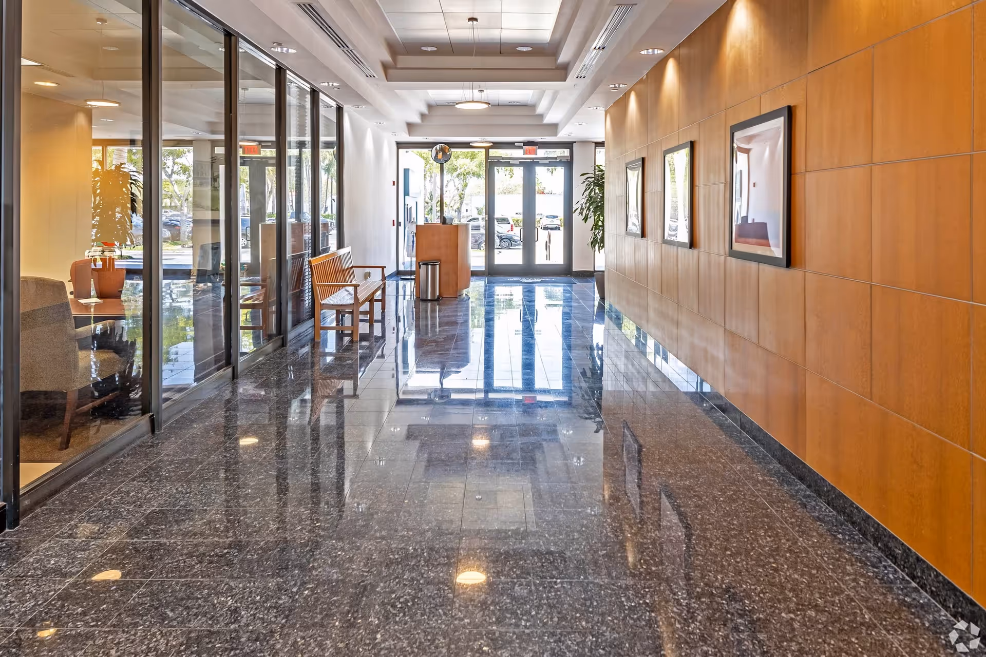 Bright modern senior living corridor with glass walls, polished floors, and wall-mounted artwork