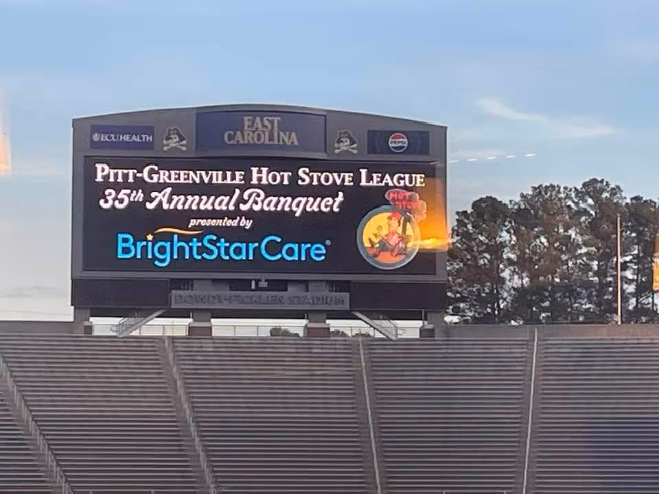 A stadium scoreboard shows BrightStarCare branding during an outdoor event.