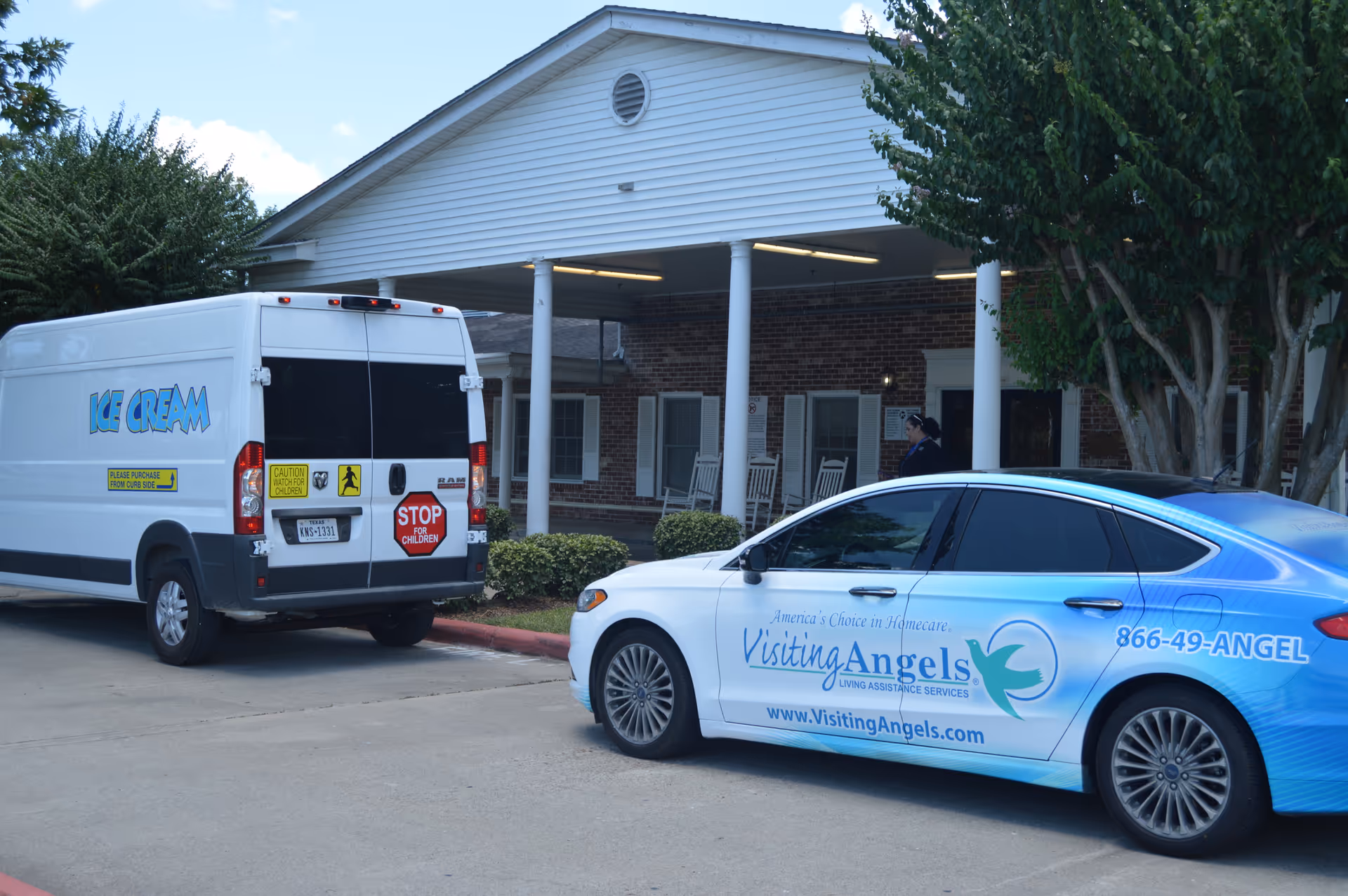 Exterior view of Visiting Angels facility with a branded car and service van parked outside.
