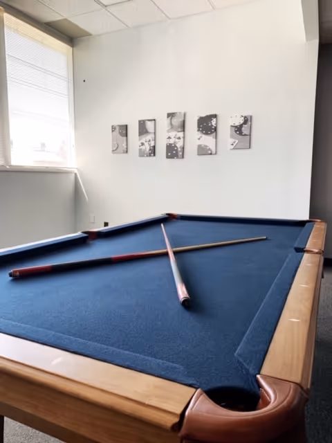 Interior recreation room with blue billiards table and wall art.