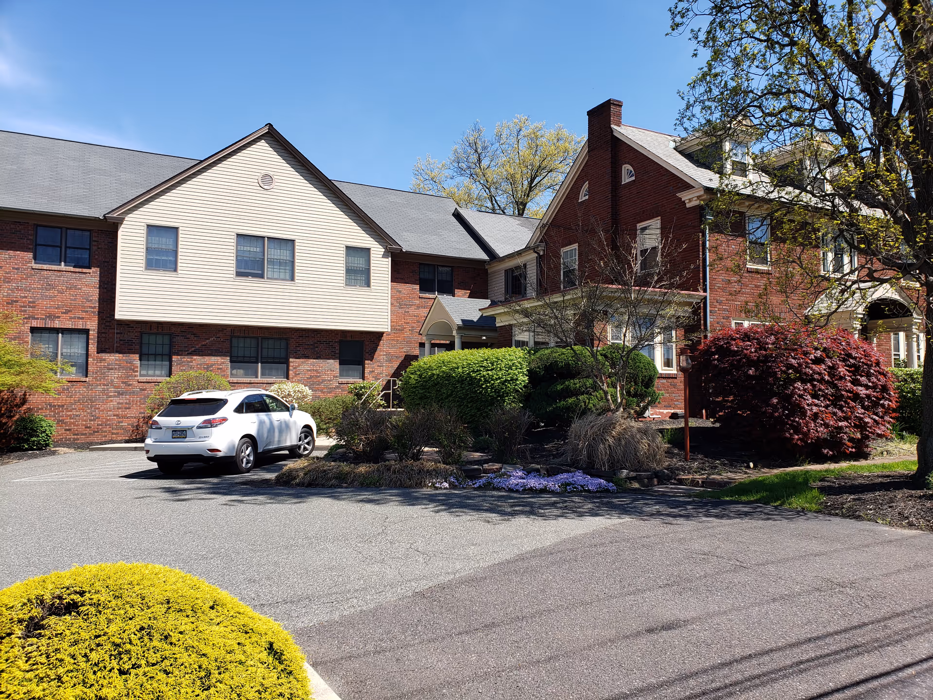 Exterior view of a brick senior living facility with parking and landscaping.