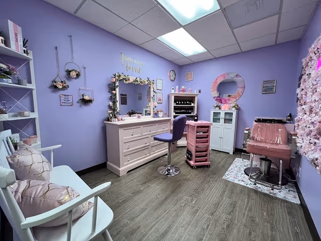 Lavender-themed salon interior with a dresser, mirror, styling chair, and pink hair station.