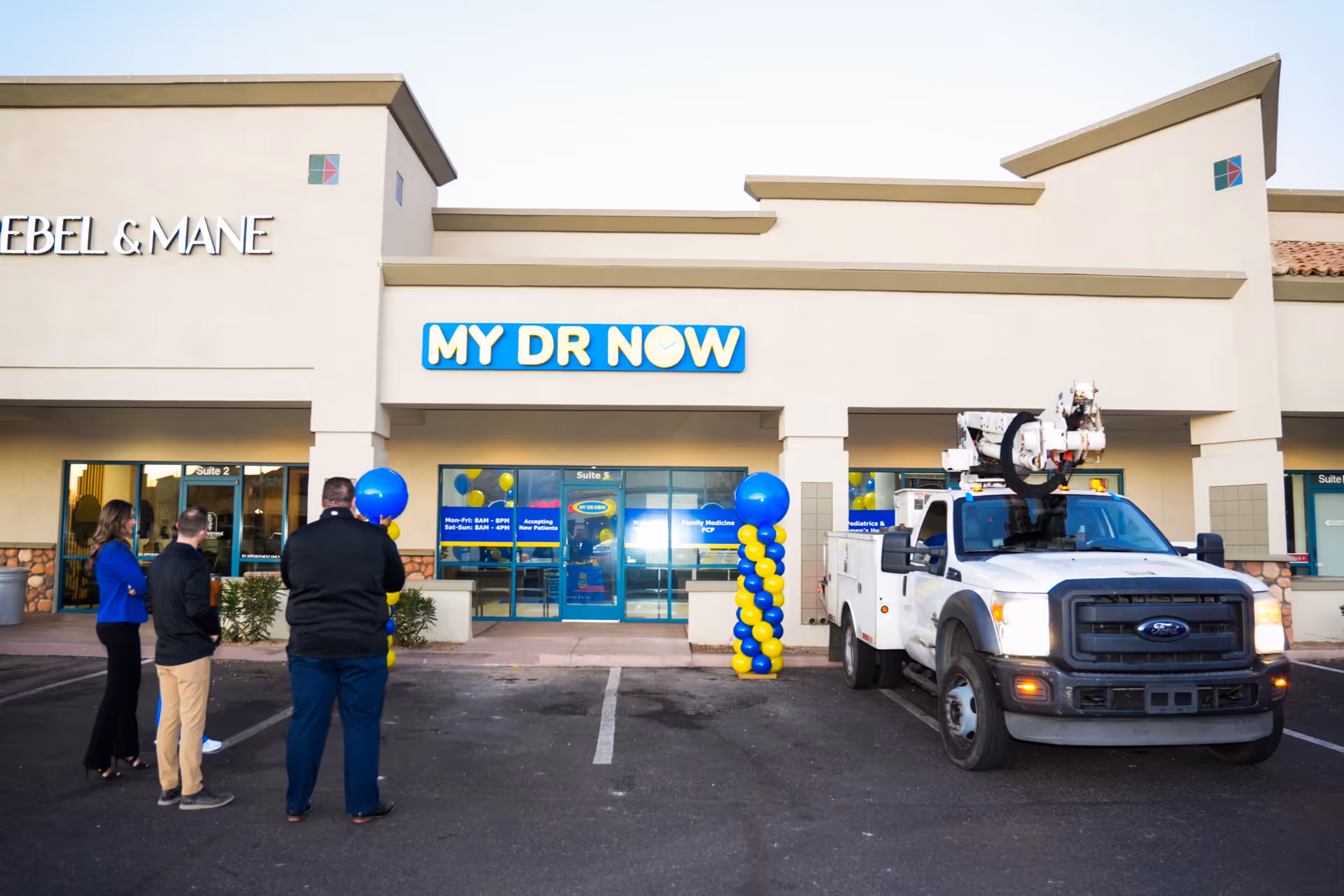 Front of a My Dr Now clinic with balloons and a truck in the parking lot.