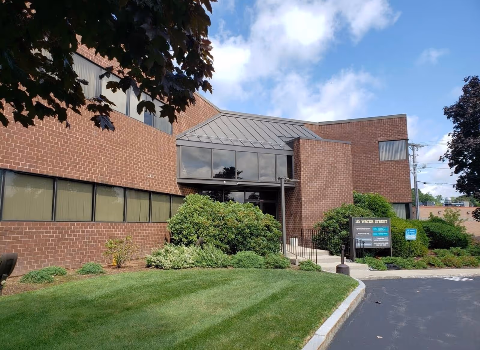 Brick senior living facility exterior with glass entrance and landscaped front yard.