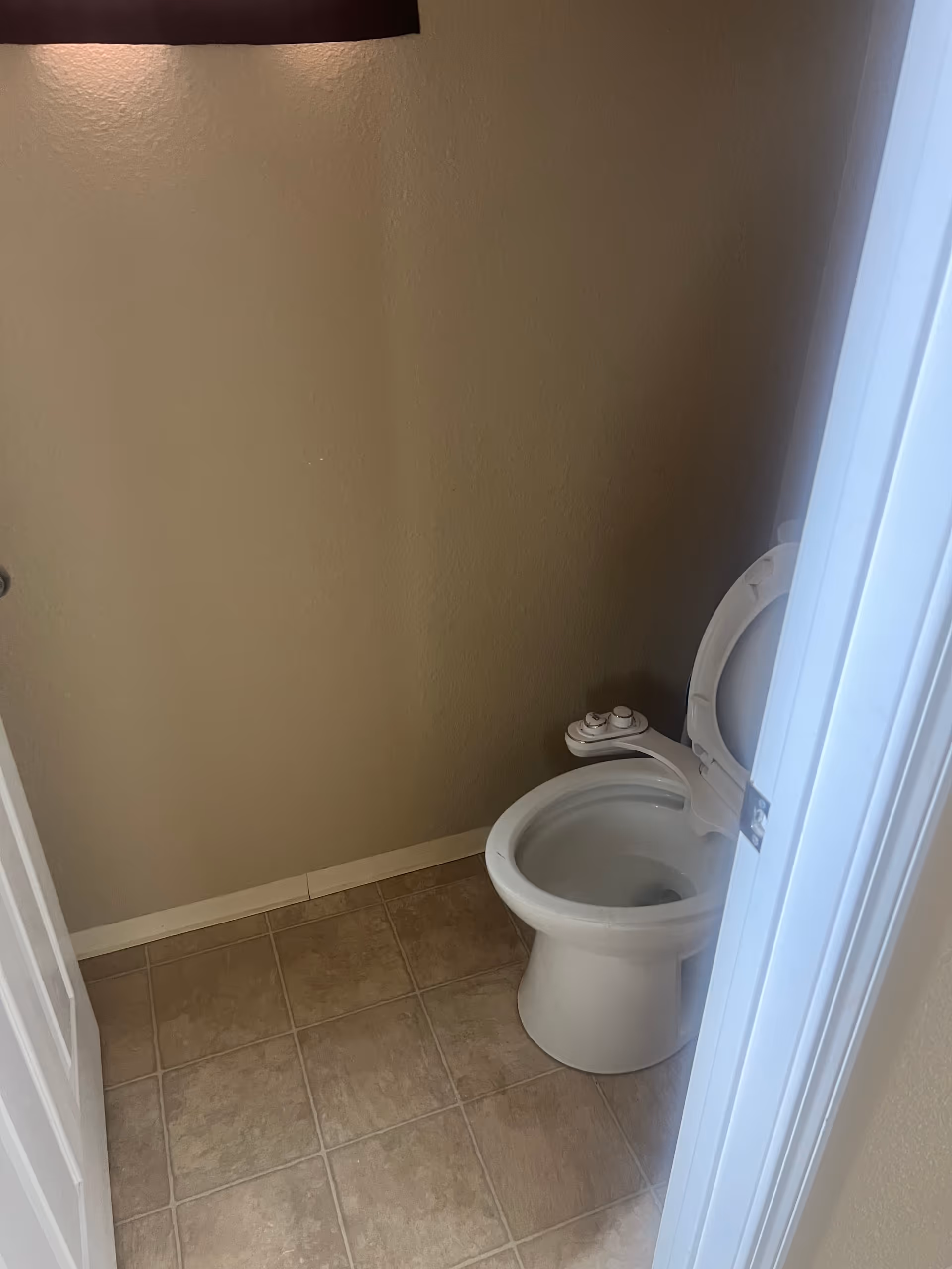 Small beige bathroom featuring a toilet and tiled floor.
