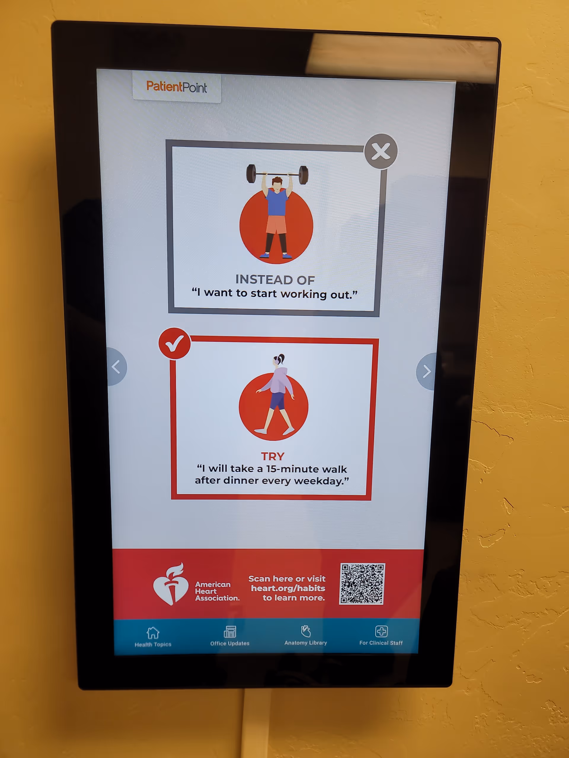 A vertical wall-mounted digital display shows fitness-themed graphics and health tips in a hallway.