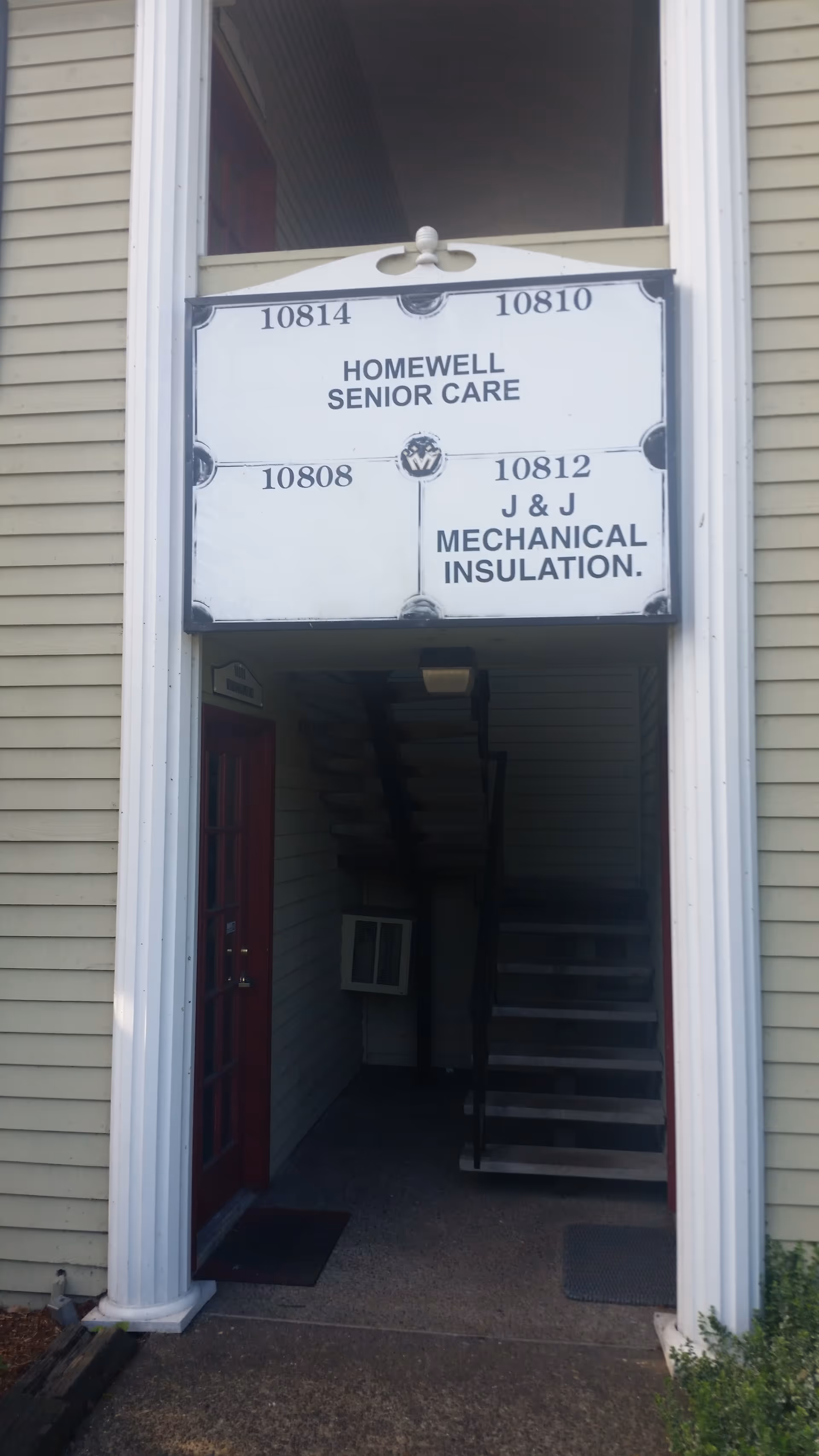 Exterior entrance of HomeWell Senior Care building with a sign and visible staircase.