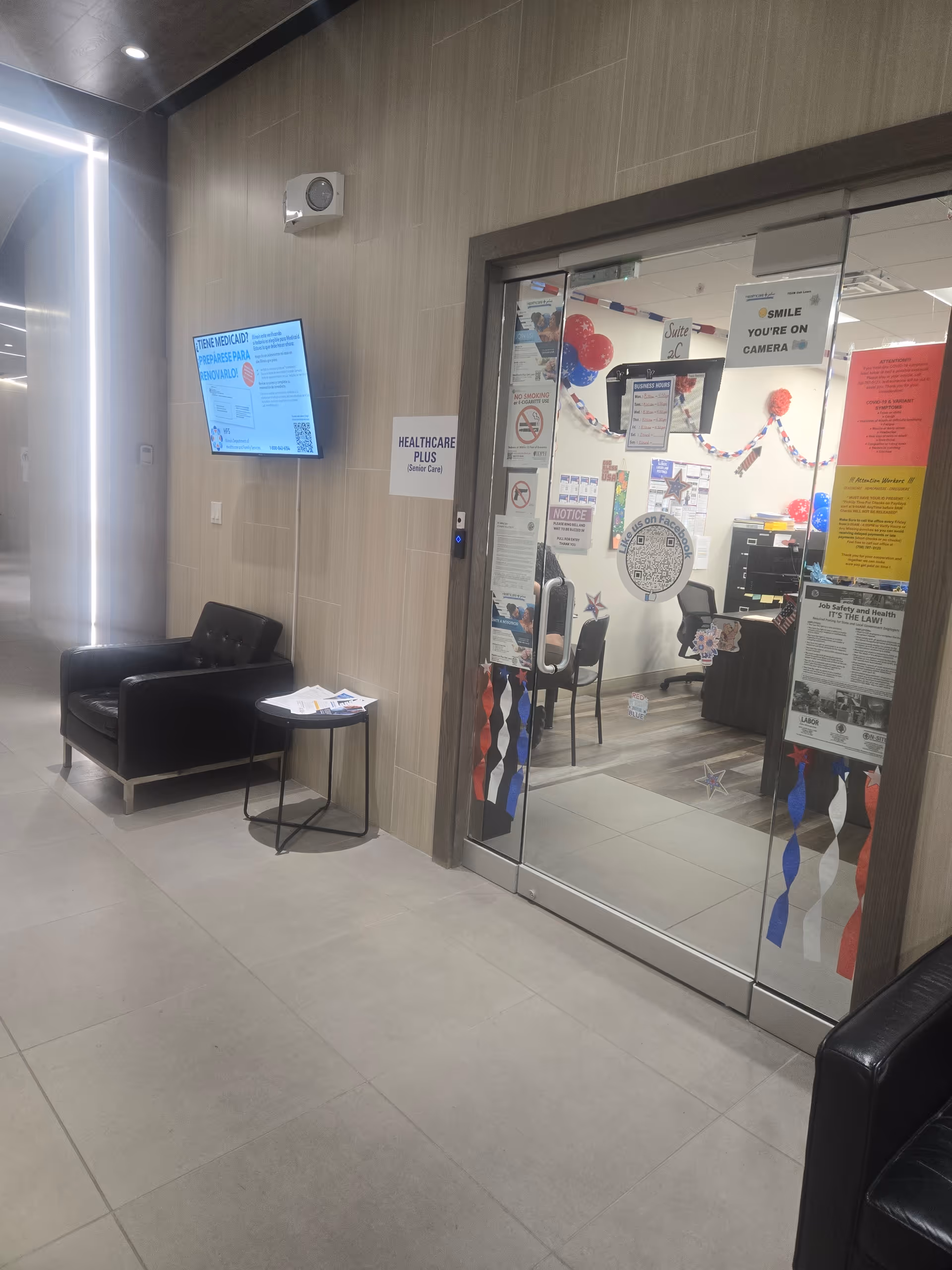 Lobby area of Healthcare Plus Caregivers with seating, wall screen, glass entrance.