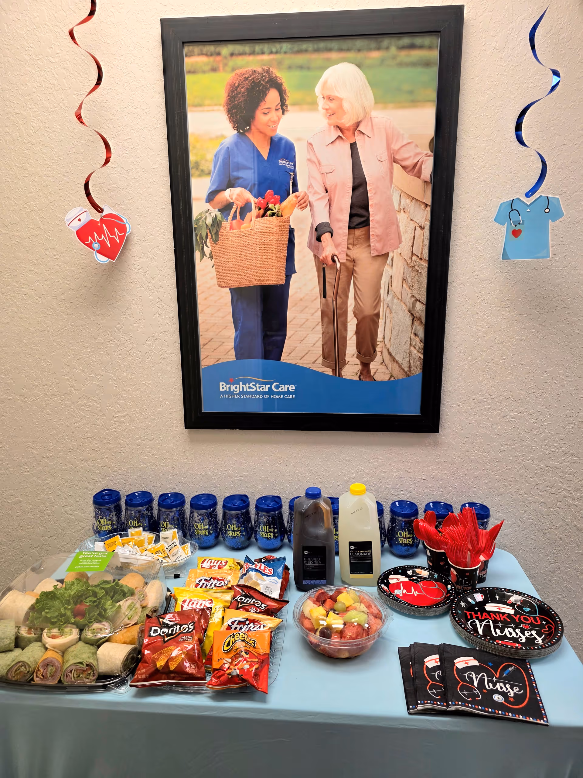 Framed BrightStar Care poster on wall above a snack table with beverages and chips.