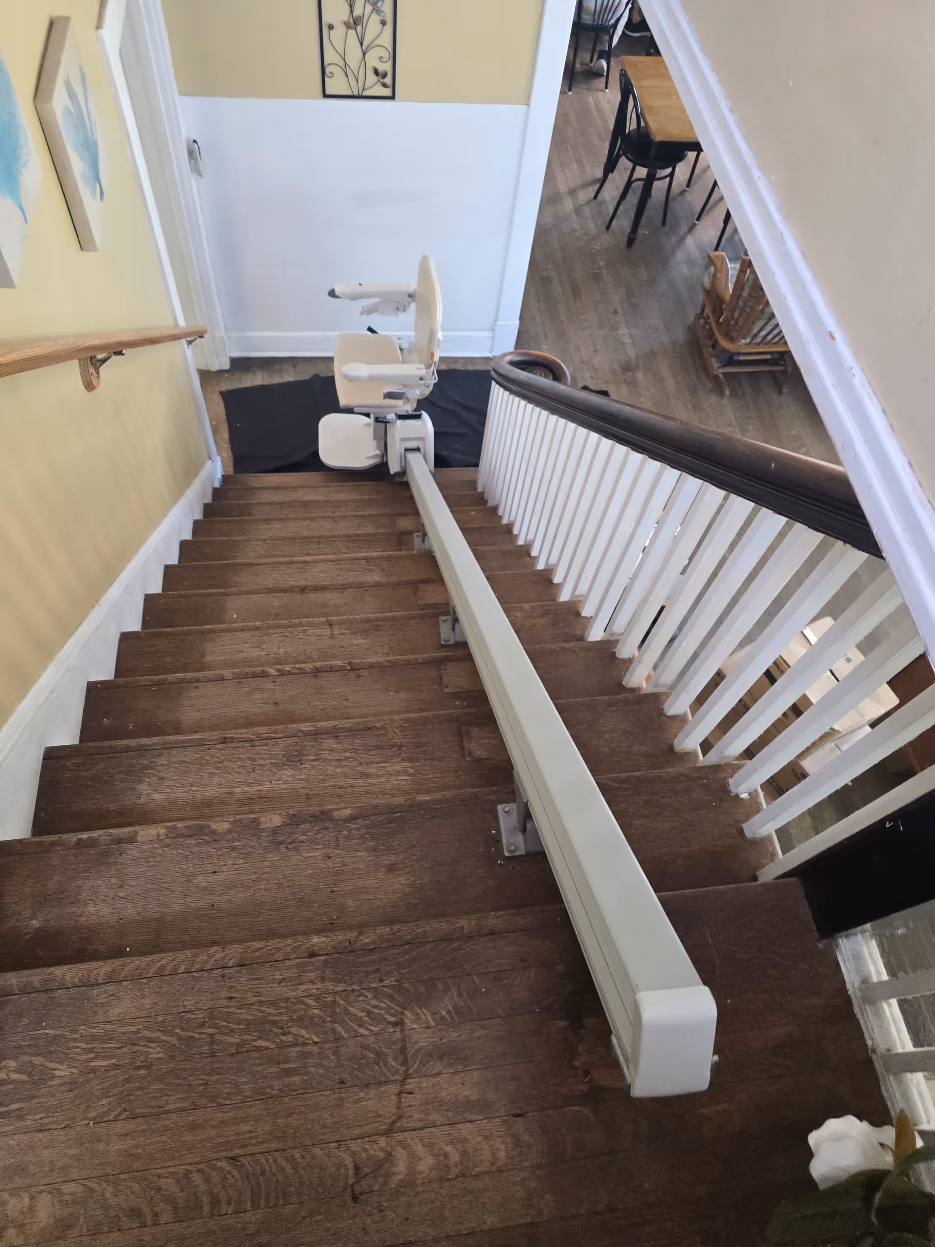 Indoor staircase with a mounted chair lift along a white railing.