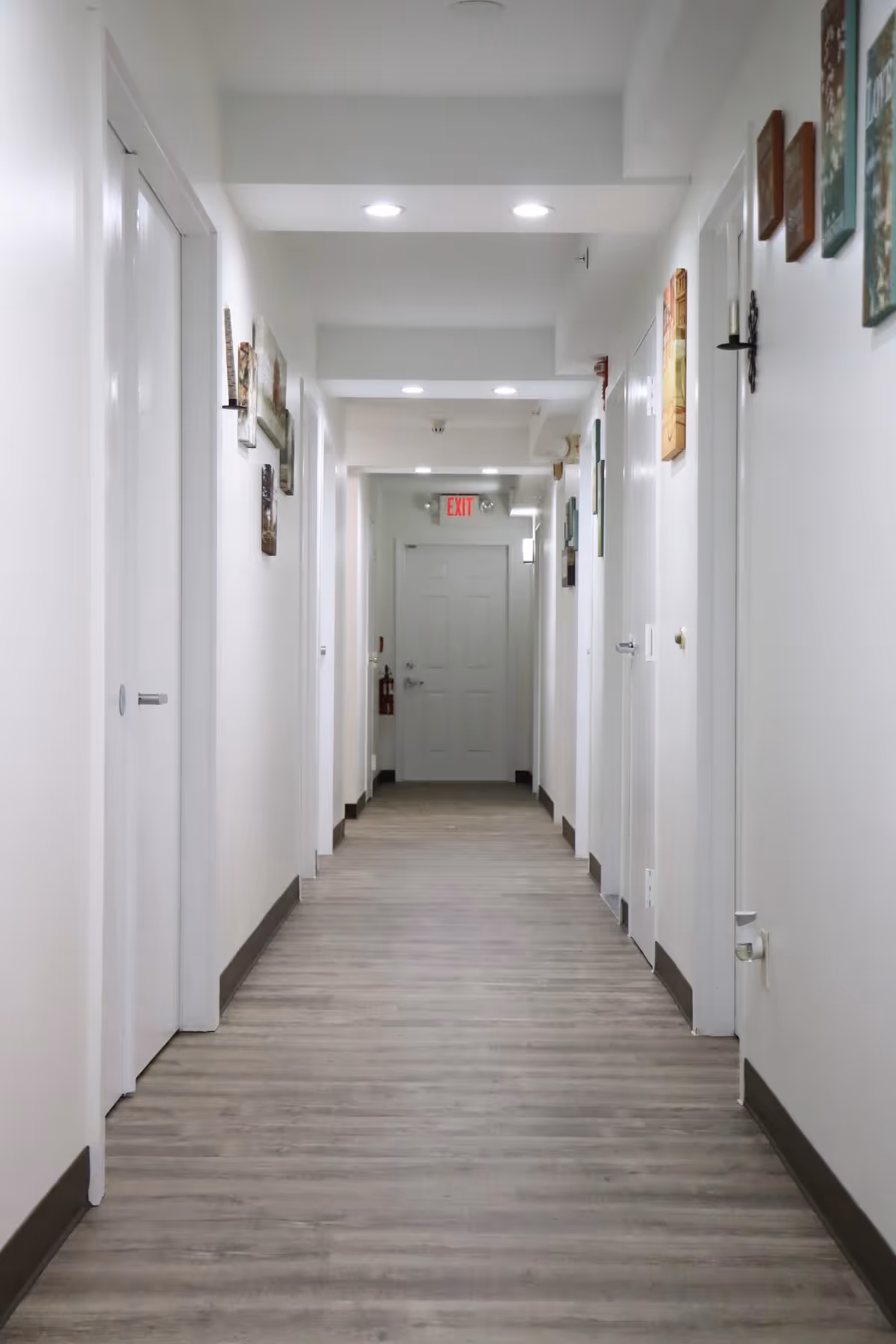 Bright white hallway in a senior living facility with doors along both walls