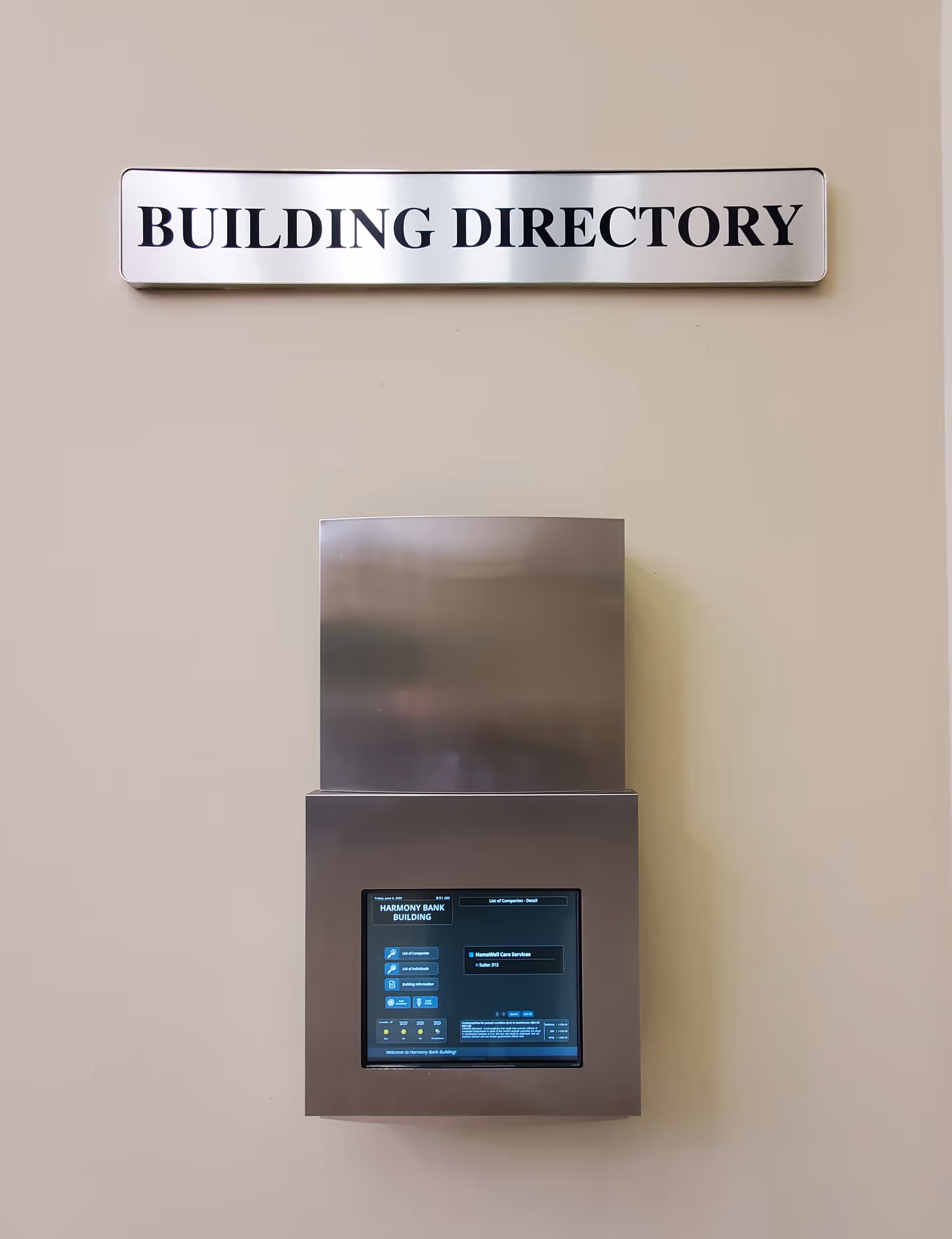 Beige wall with a stainless steel building directory panel and touchscreen.