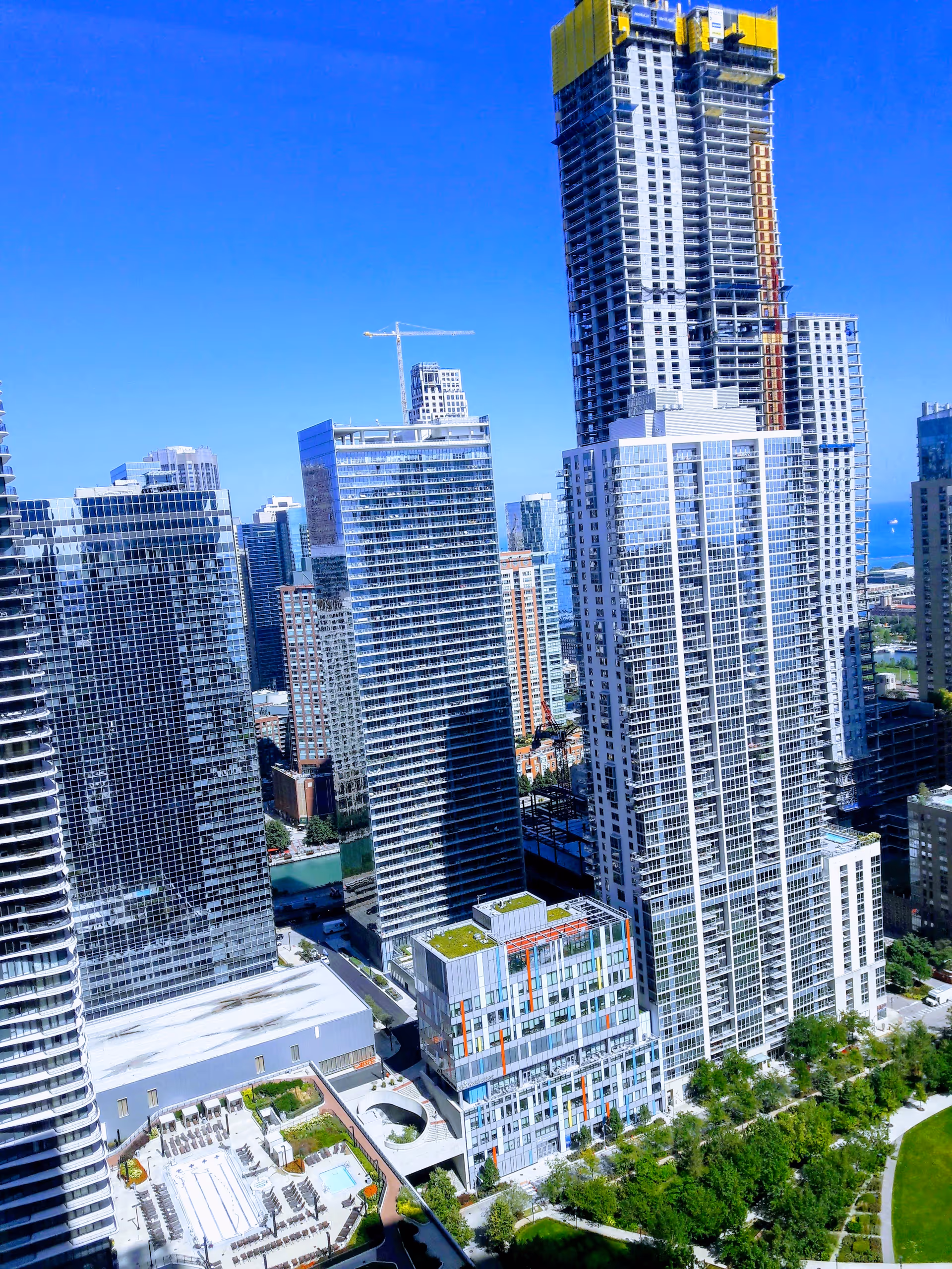 A city skyline of high-rise buildings with a construction crane under a clear blue sky