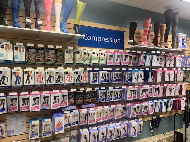 Rows of compression stockings on shelves with leg mannequins under a blue Compression sign.