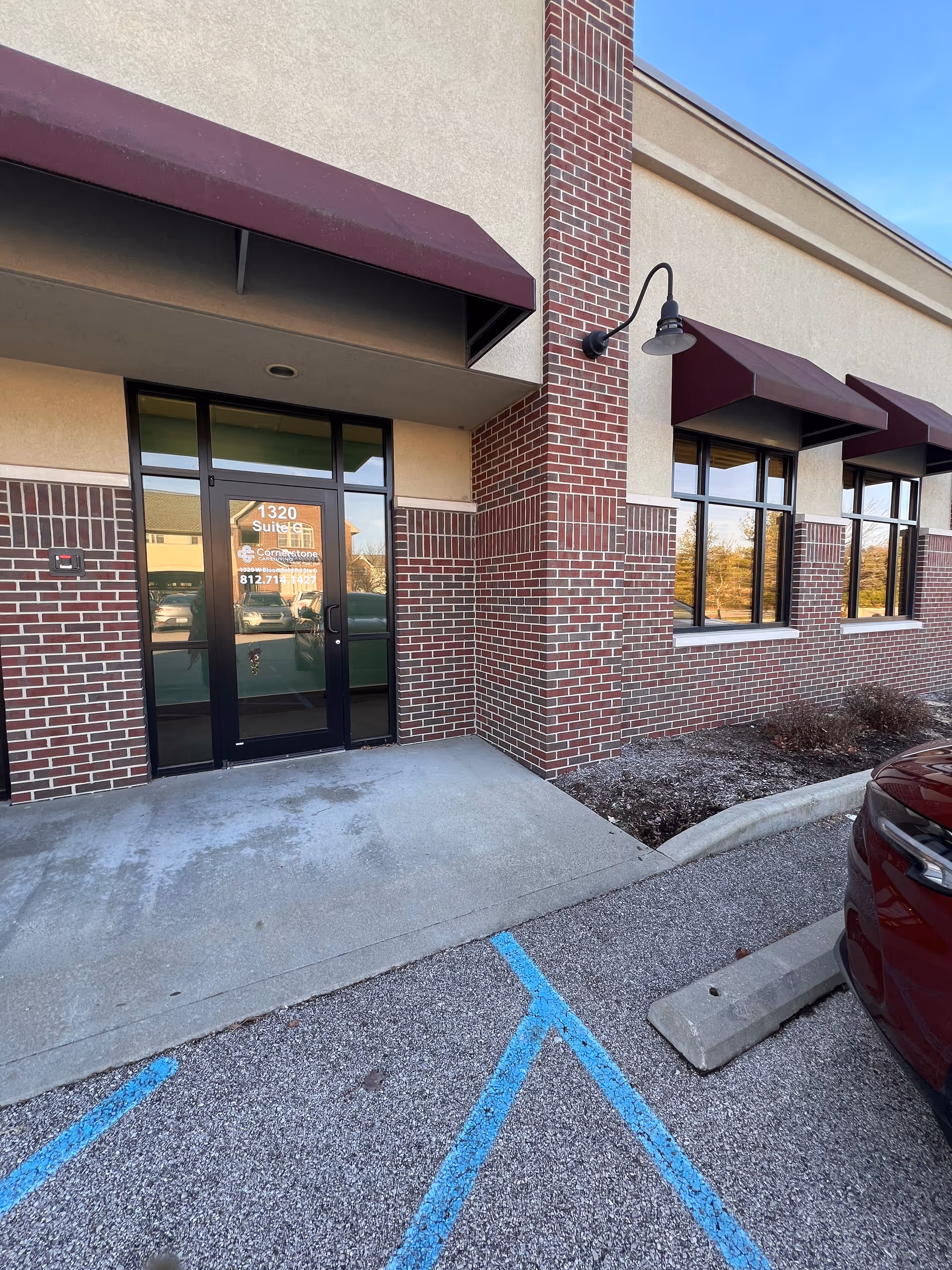 Brick facility exterior with glass entrance, brick columns, and maroon awnings.