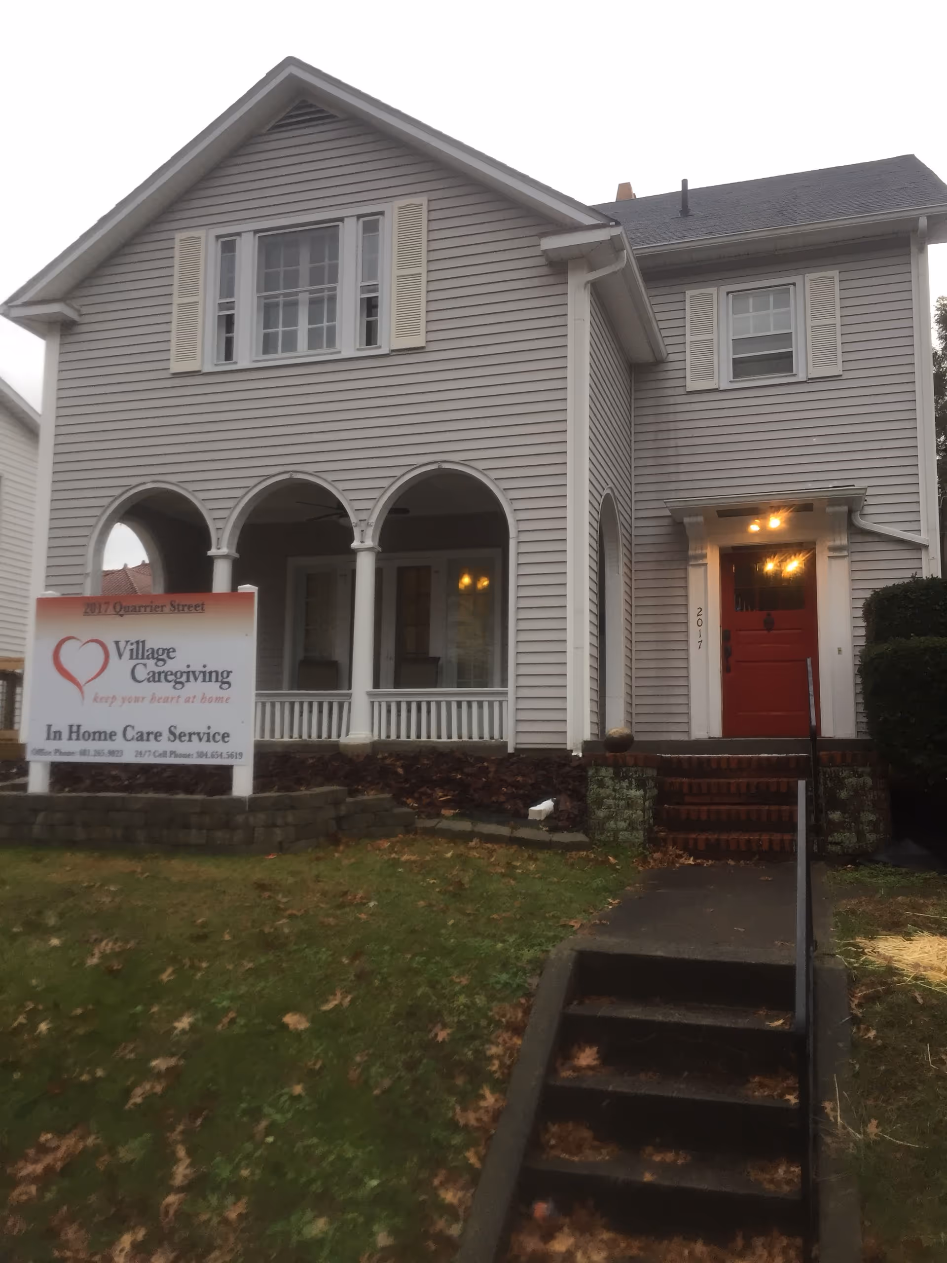 Two-story gray building with front porch arches and Village Caregiving sign.