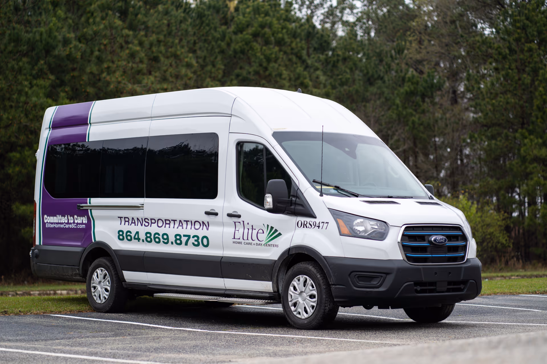 White Elite transportation van branded with Elite Home Care & Day Centers parked in a lot.