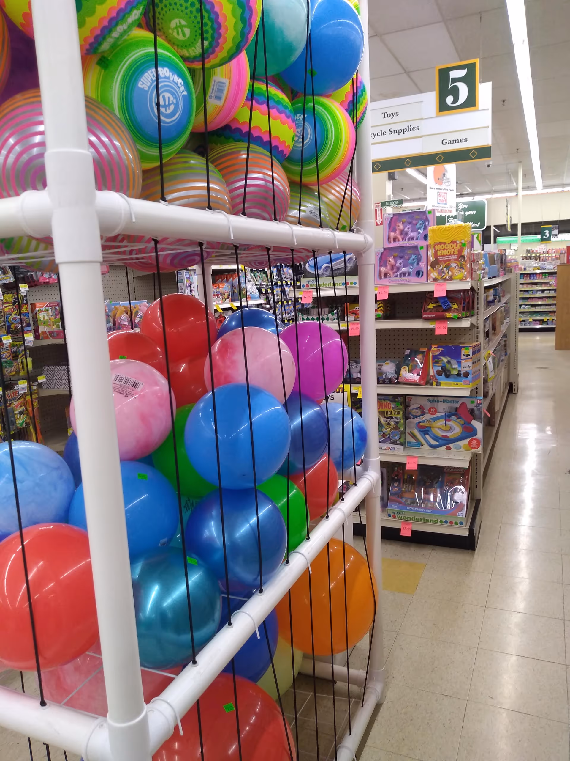 Colorful balls and toys fill shelves inside a Discount Drug Mart store.