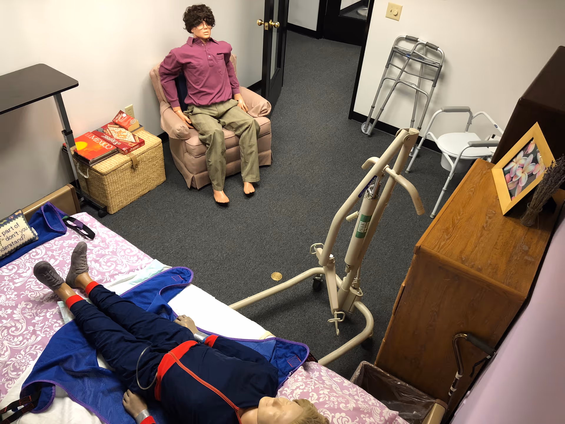 A small care room with a bed, a walker, and two mannequins.