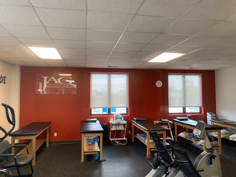 Therapy room with red wall, JAG Physical Therapy sign, and exercise equipment.