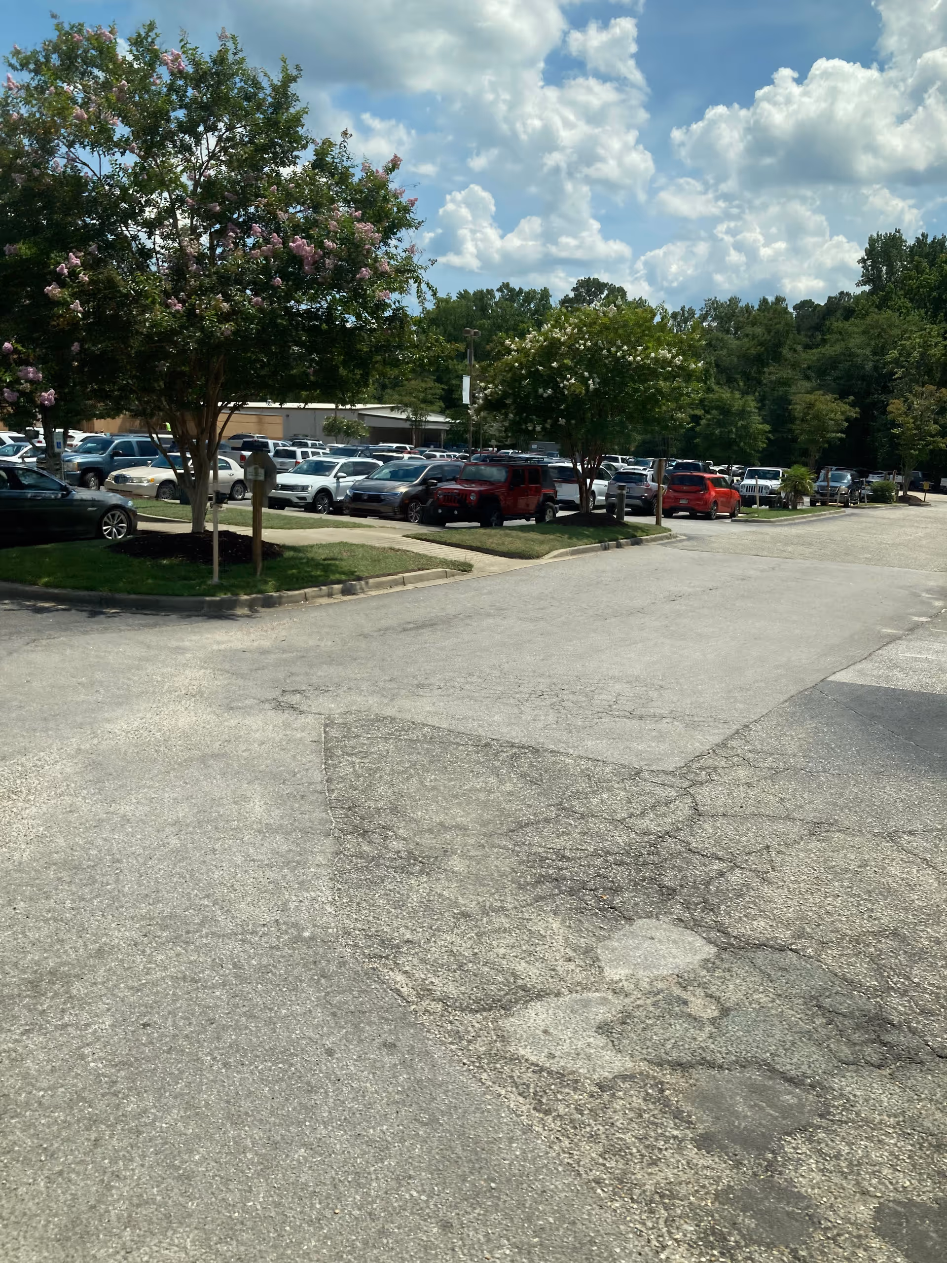 Parking lot outside MUSC Health Kershaw Medical Center with cars and trees