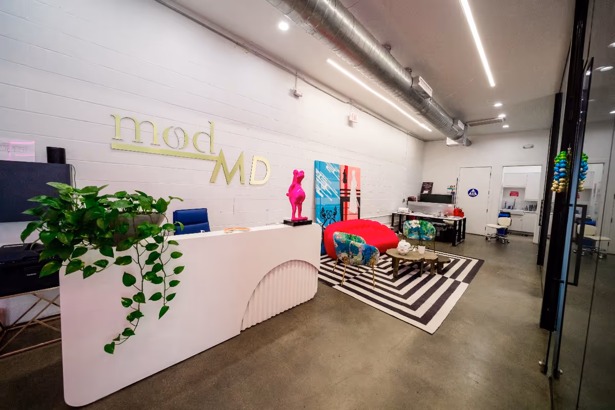 Reception lobby with a modMD sign, plants, colorful seating, and geometric striped rug.