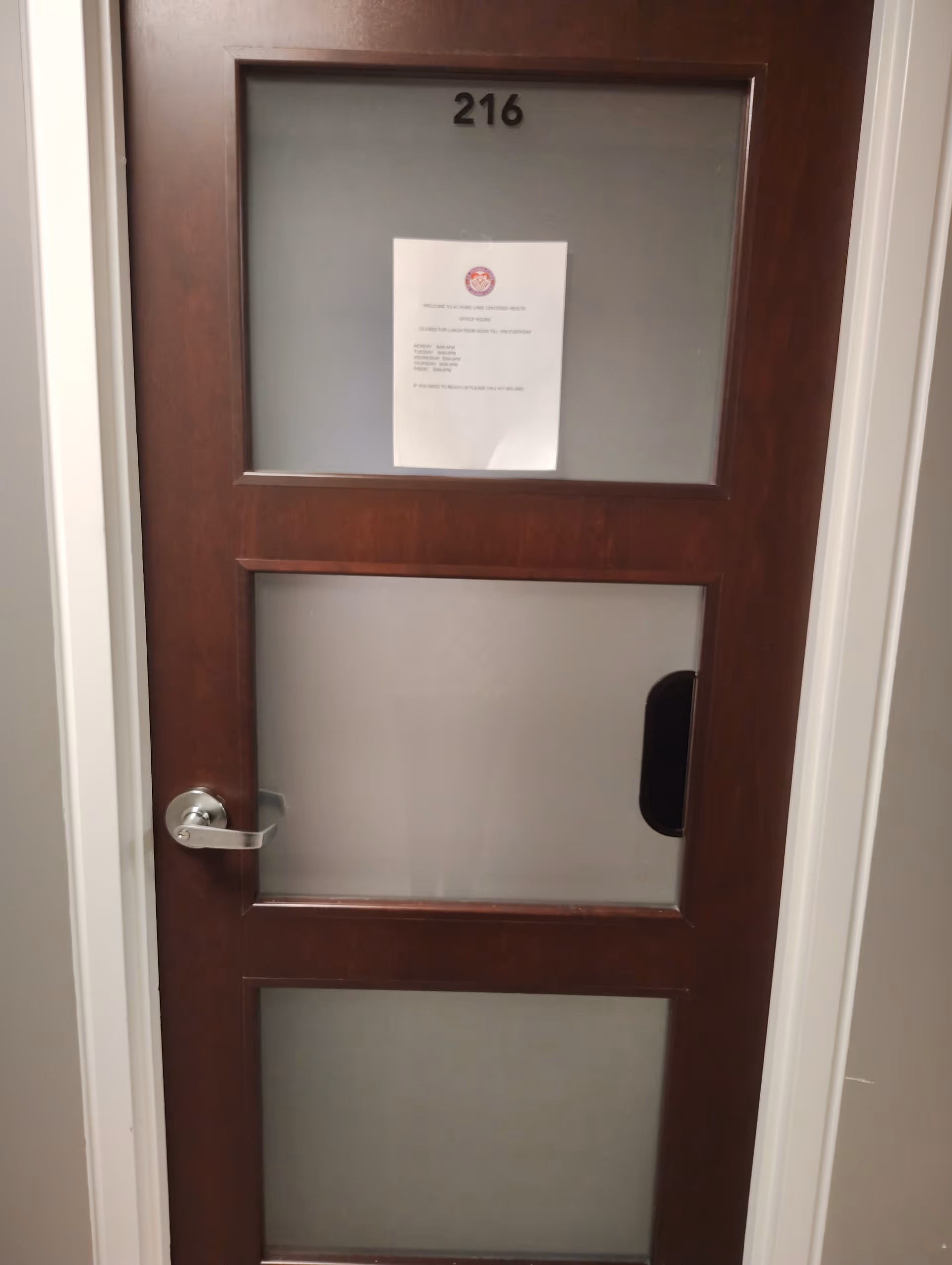 Wooden interior door with frosted glass panels labeled 216 and a posted notice