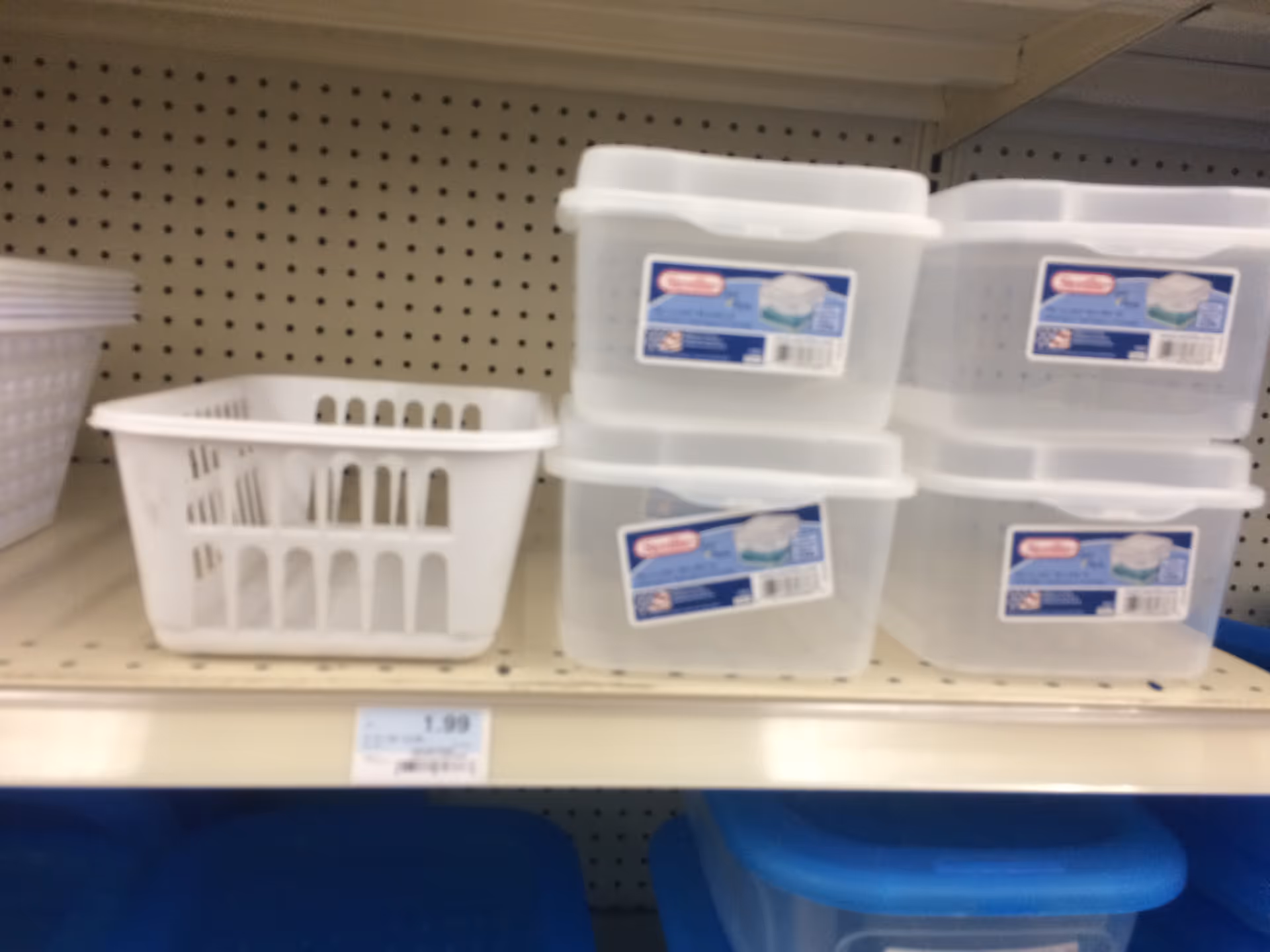 Shelf with a white basket and stacked clear plastic containers on pegboard.