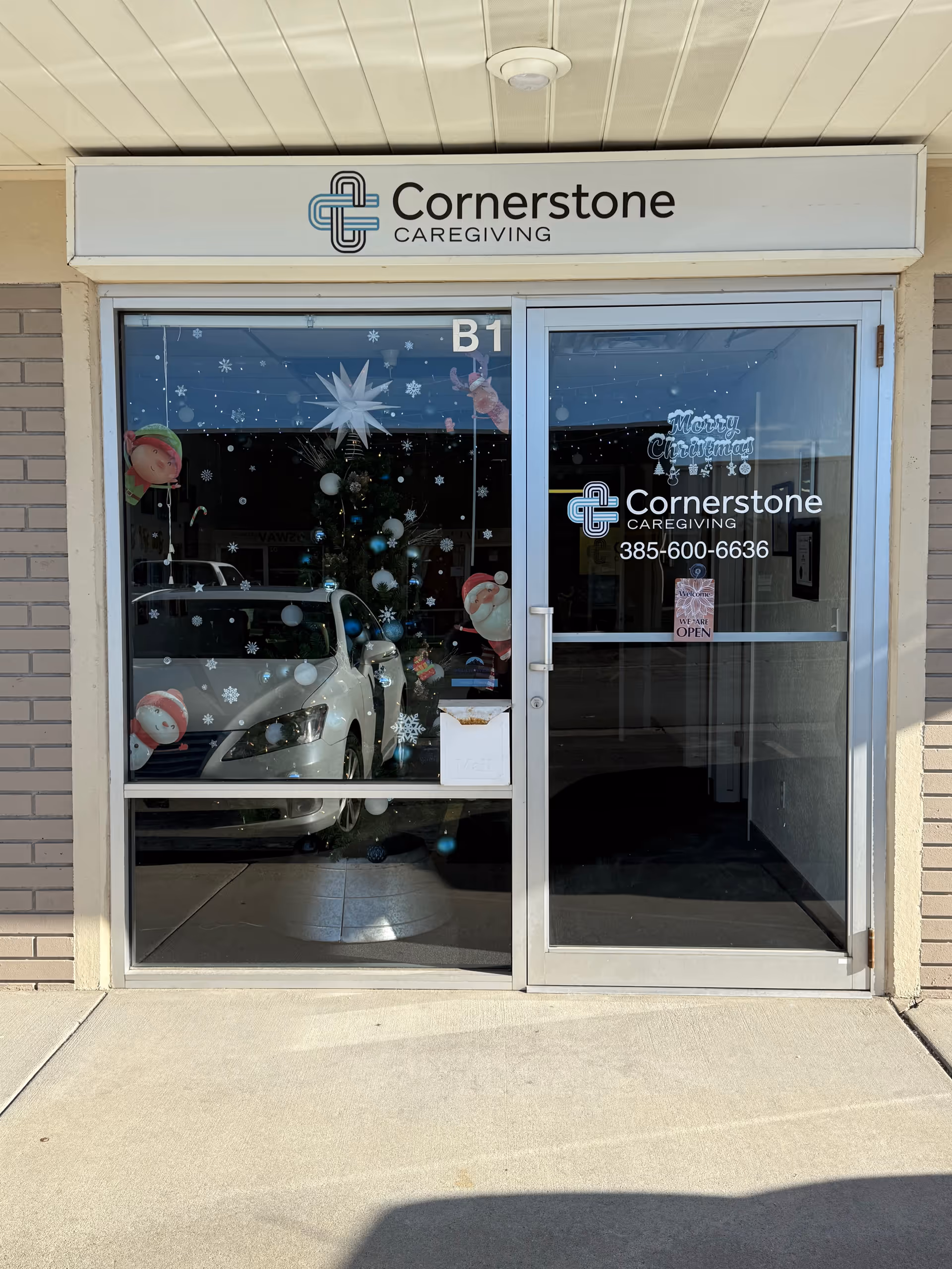 Exterior storefront of Cornerstone Caregiving featuring glass doors and holiday decorations