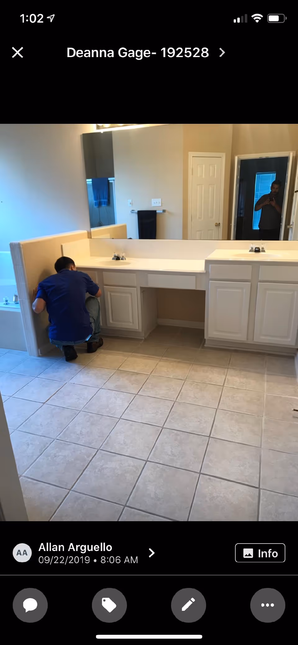 Maintenance worker kneels by a bathroom vanity during renovation at a senior living facility.