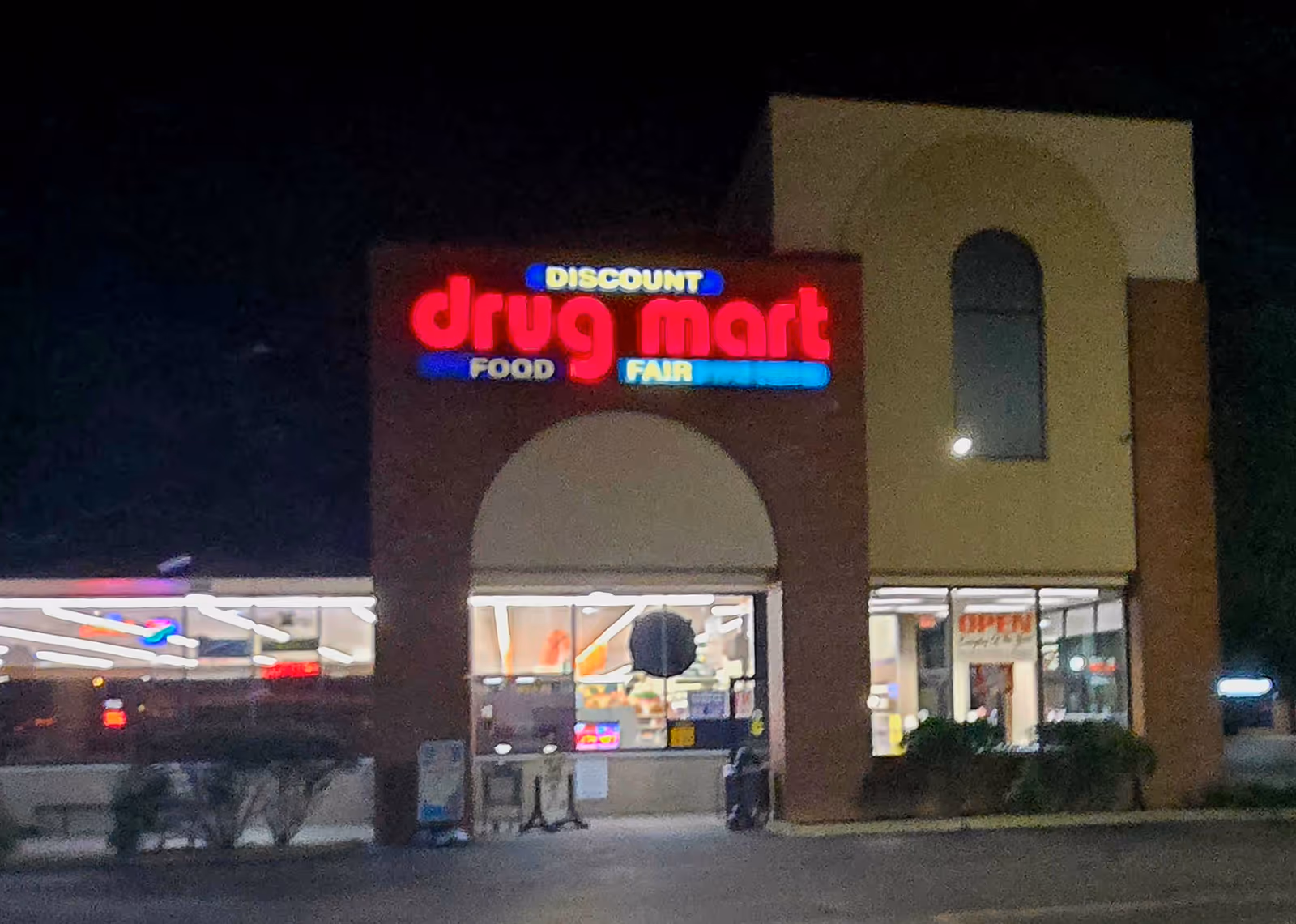 Nighttime exterior view of Discount Drug Mart with illuminated sign and entrance.