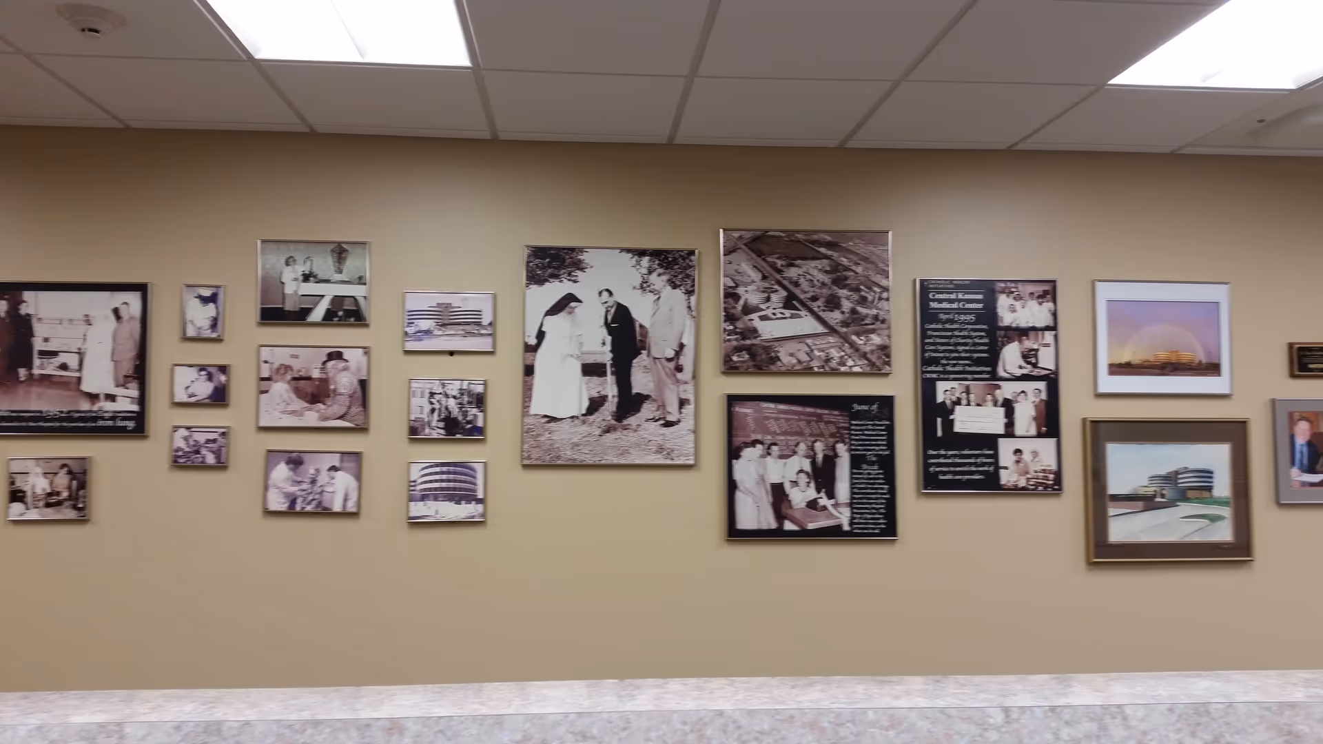 Interior hallway of St. Rose Health Center with a wall of framed photos and informational panels.