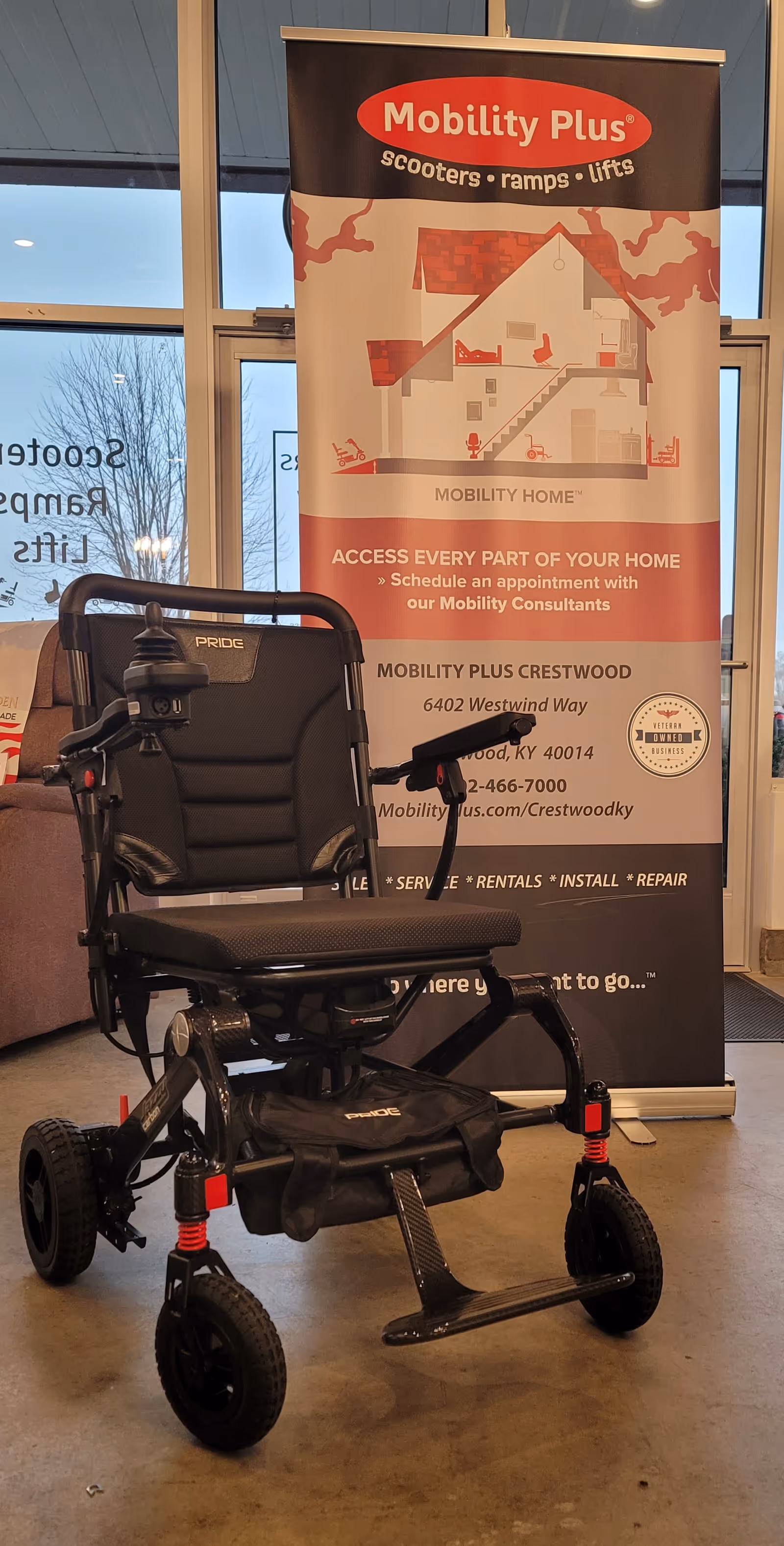 A mobility scooter on display inside a facility with a Mobility Plus banner.