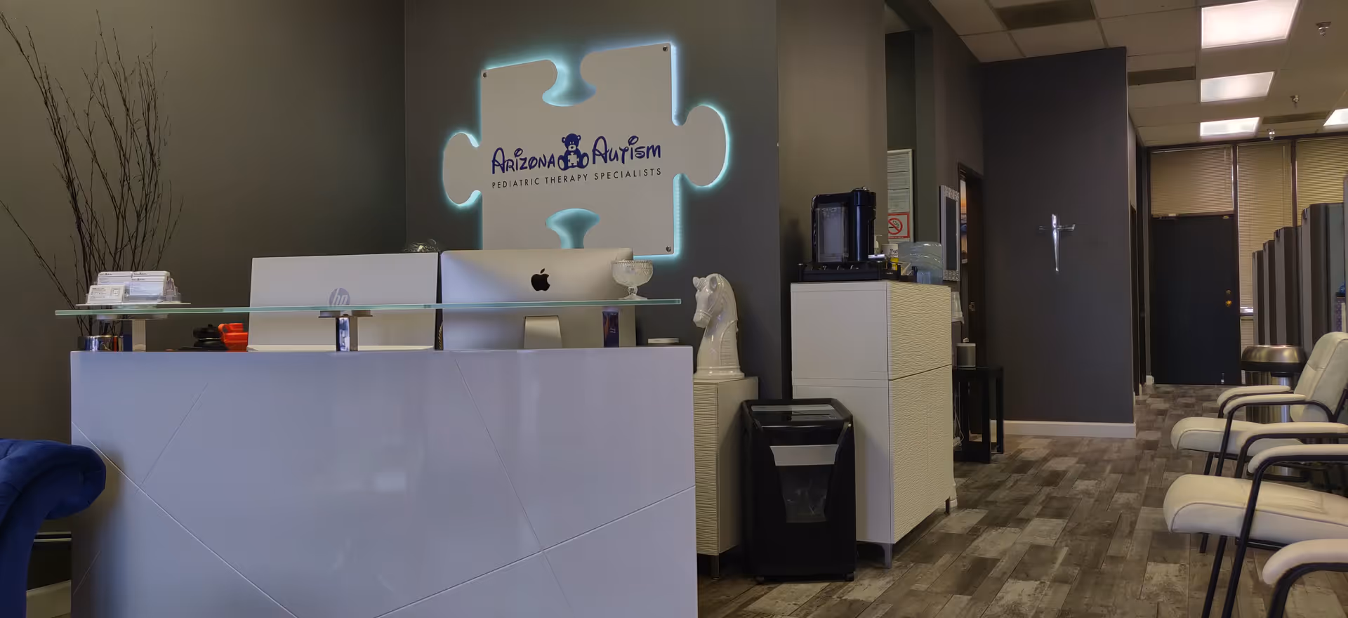 Interior reception area featuring an illuminated Arizona Autism sign and waiting chairs.