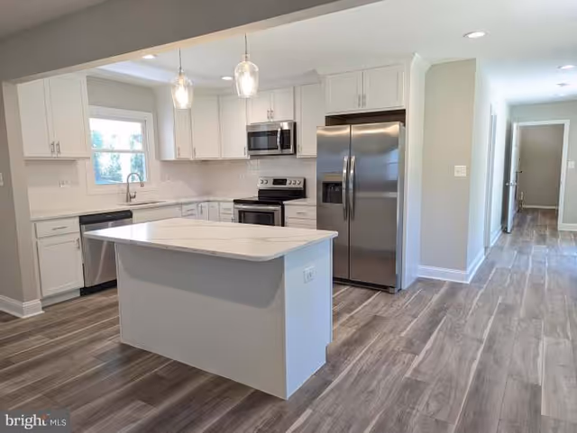 Bright modern kitchen in a senior living facility with white cabinets and stainless appliances.