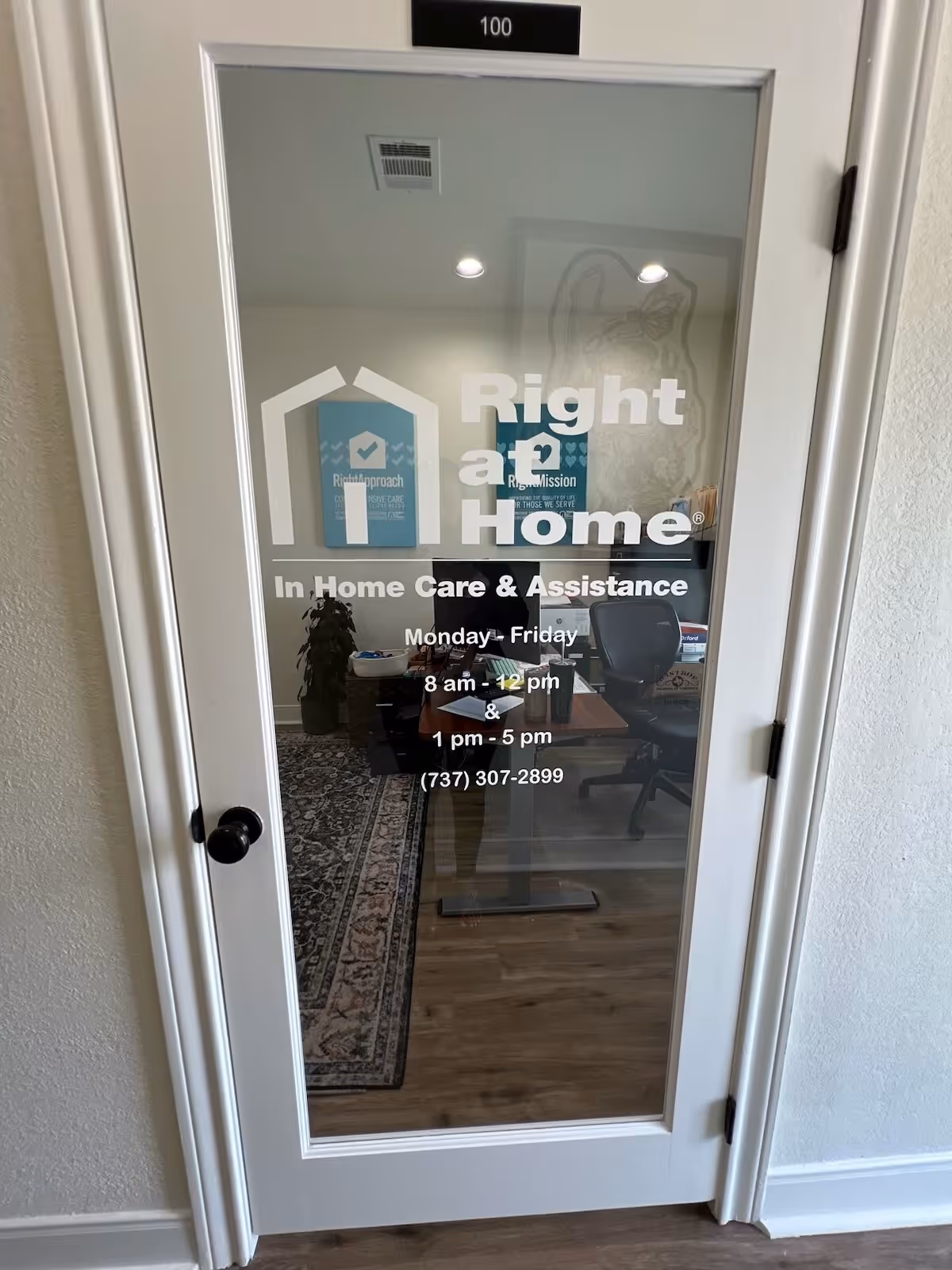 Glass door with Right at Home logo reveals an office space with desk and chairs.