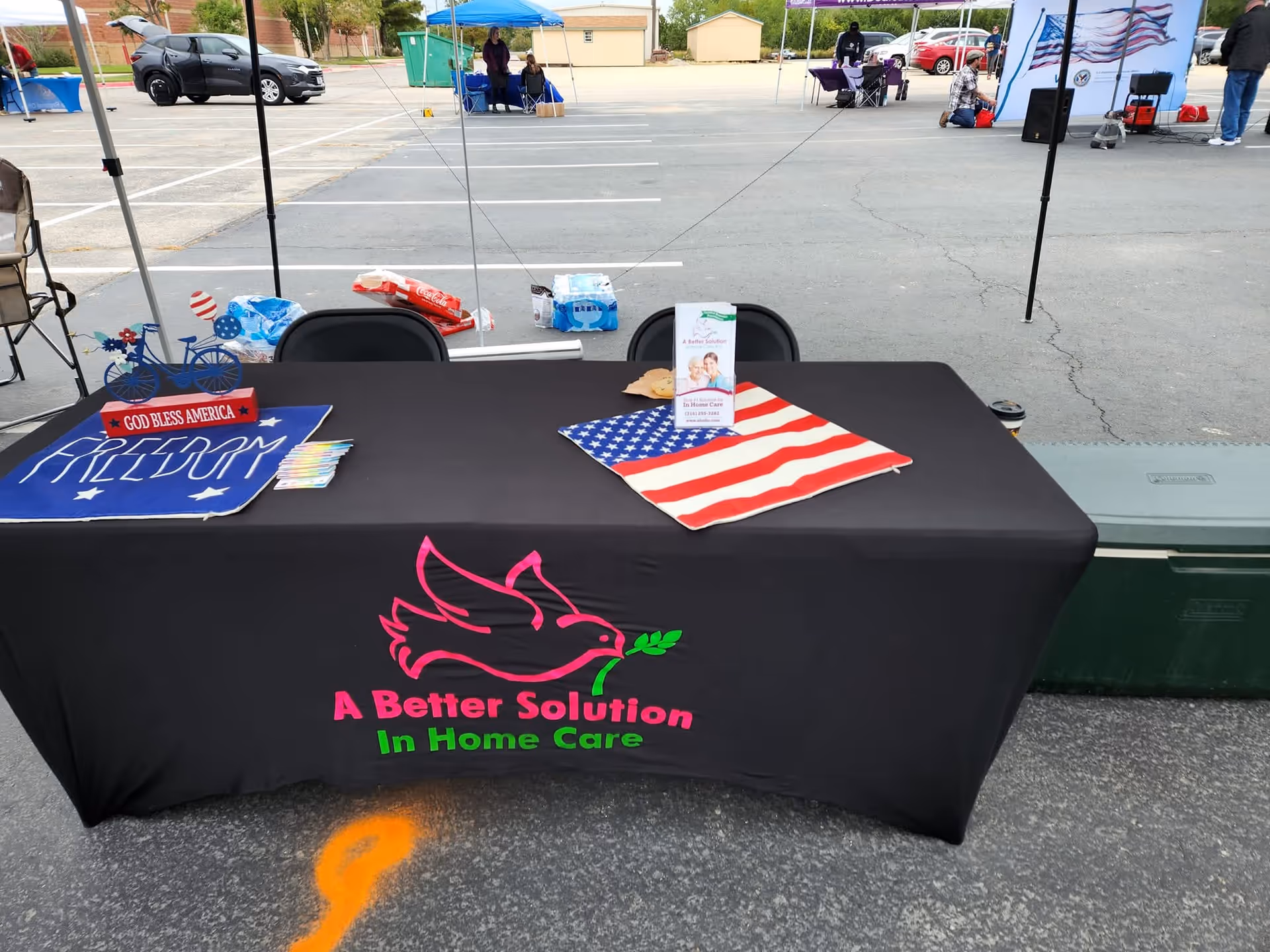 Outdoor booth table displays the A Better Solution In Home Care logo on a black tablecloth.