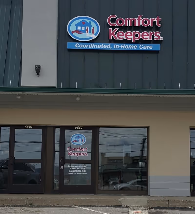 Front of a Comfort Keepers building with logo sign and glass doors.