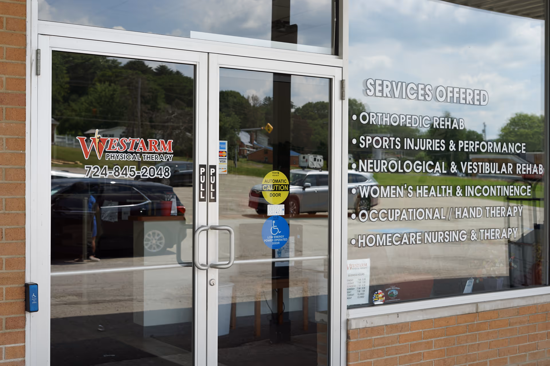 Front entrance of WESTARM Physical Therapy with glass doors and service list on window