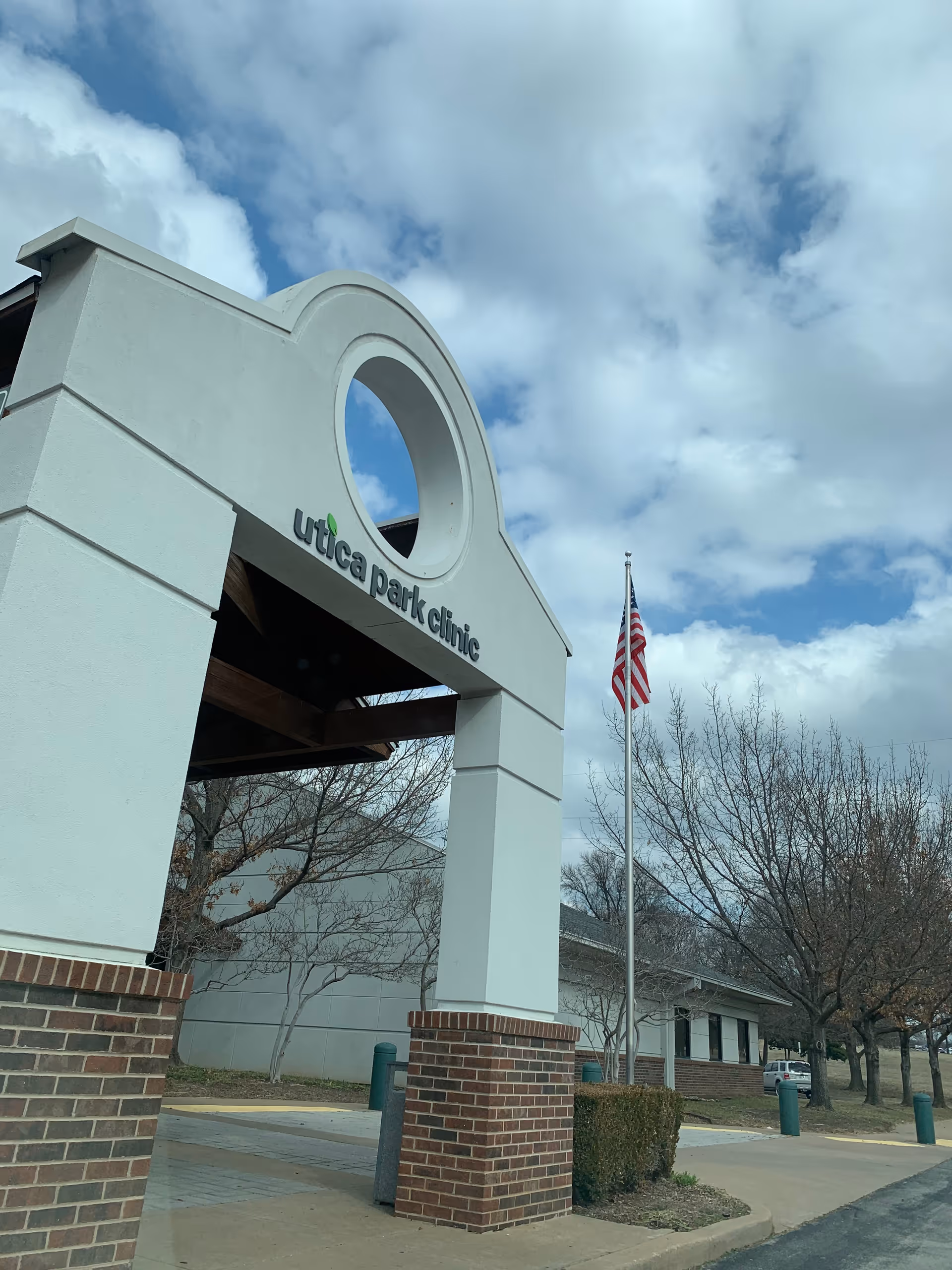 Exterior view of a clinic entrance with brick pillars and a flag