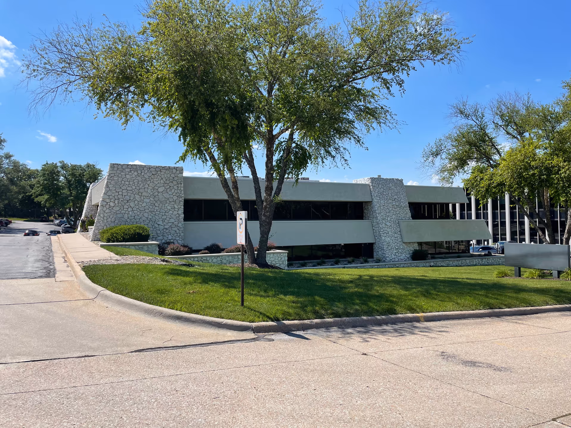 Front view of a modern senior living facility with stone accents and trees.